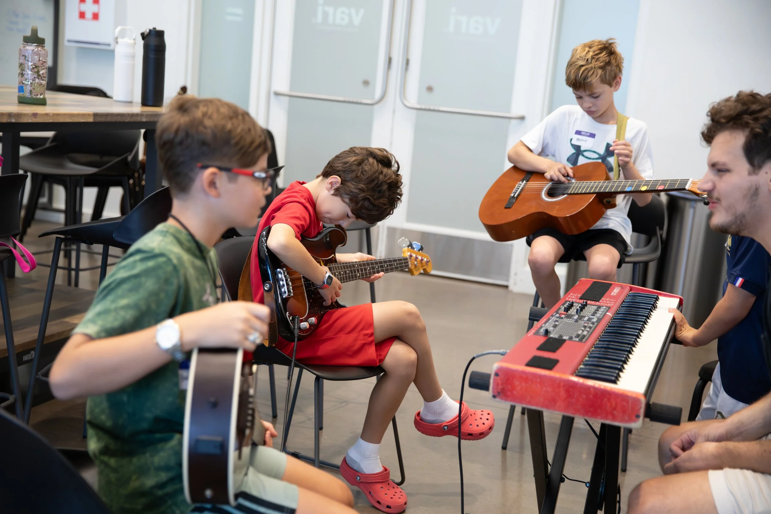 A group of children and an adult playing musical instruments in a classroom.