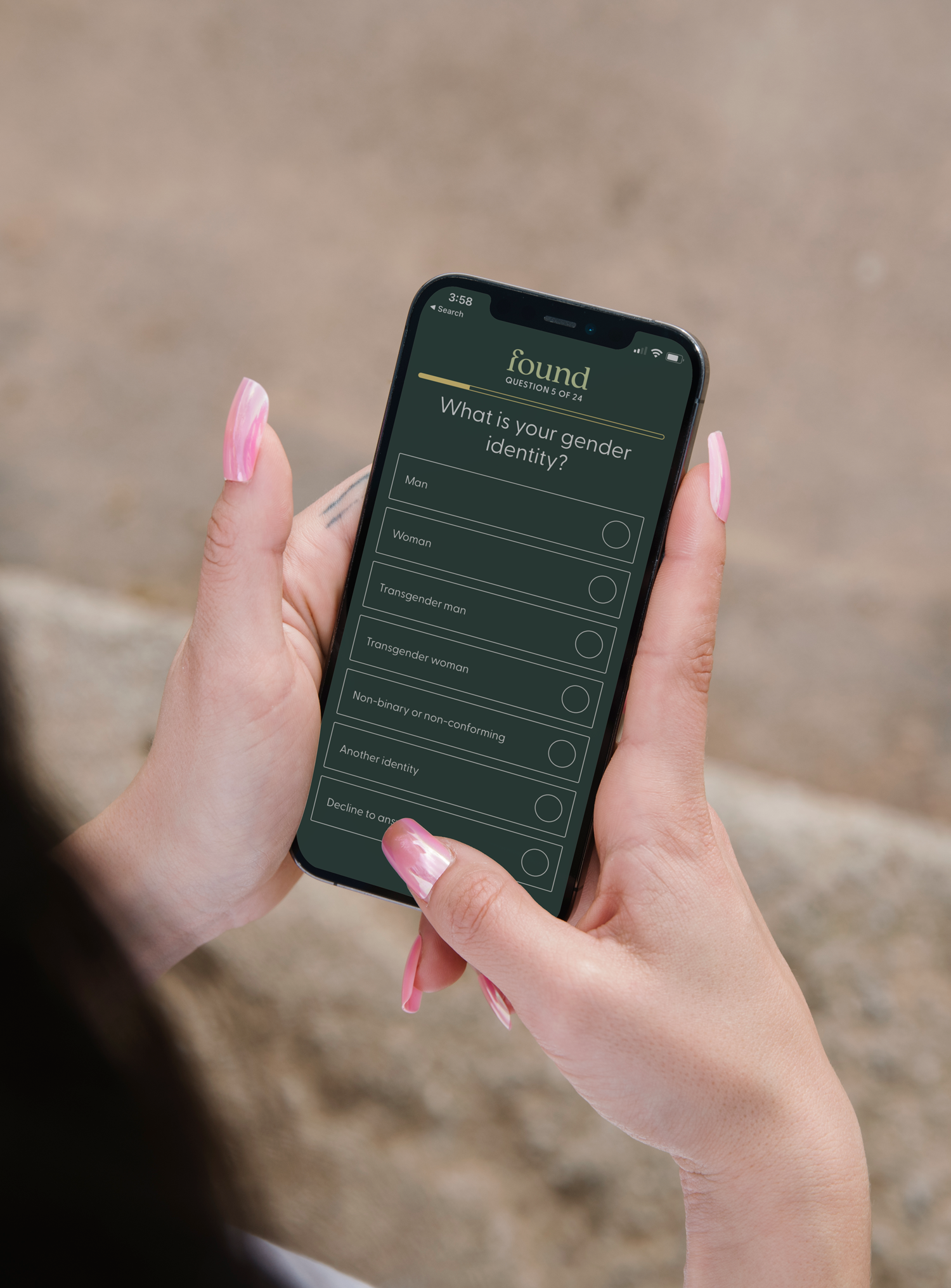 Person holding a smartphone displaying a gender identity quiz with options for Man, Woman, Transgender man, Transgender woman, Non-binary or non-conforming, Another identity, and Decline to answer.