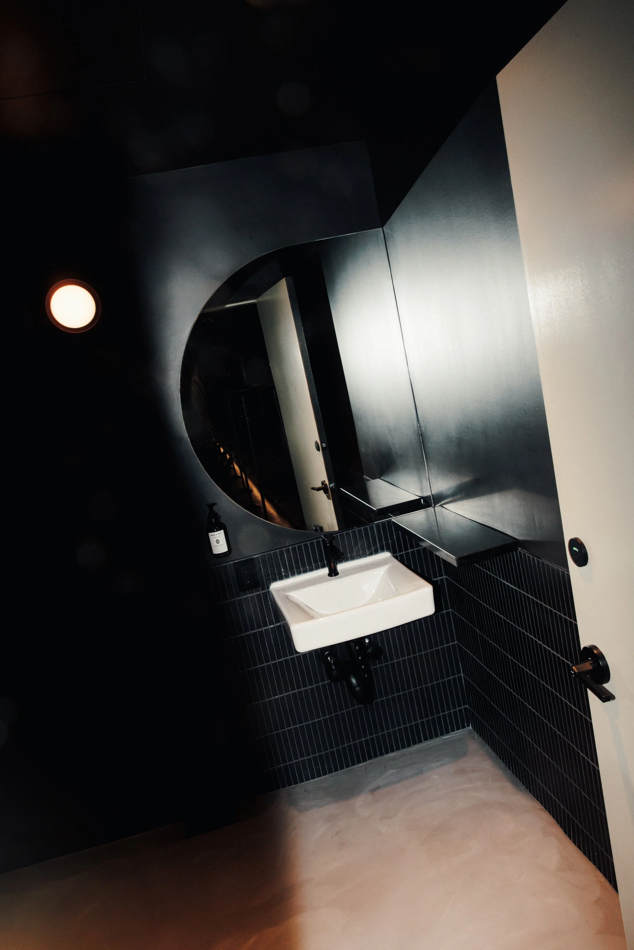 Bright flash in a black bathroom with half tiling and a semi circle mirror