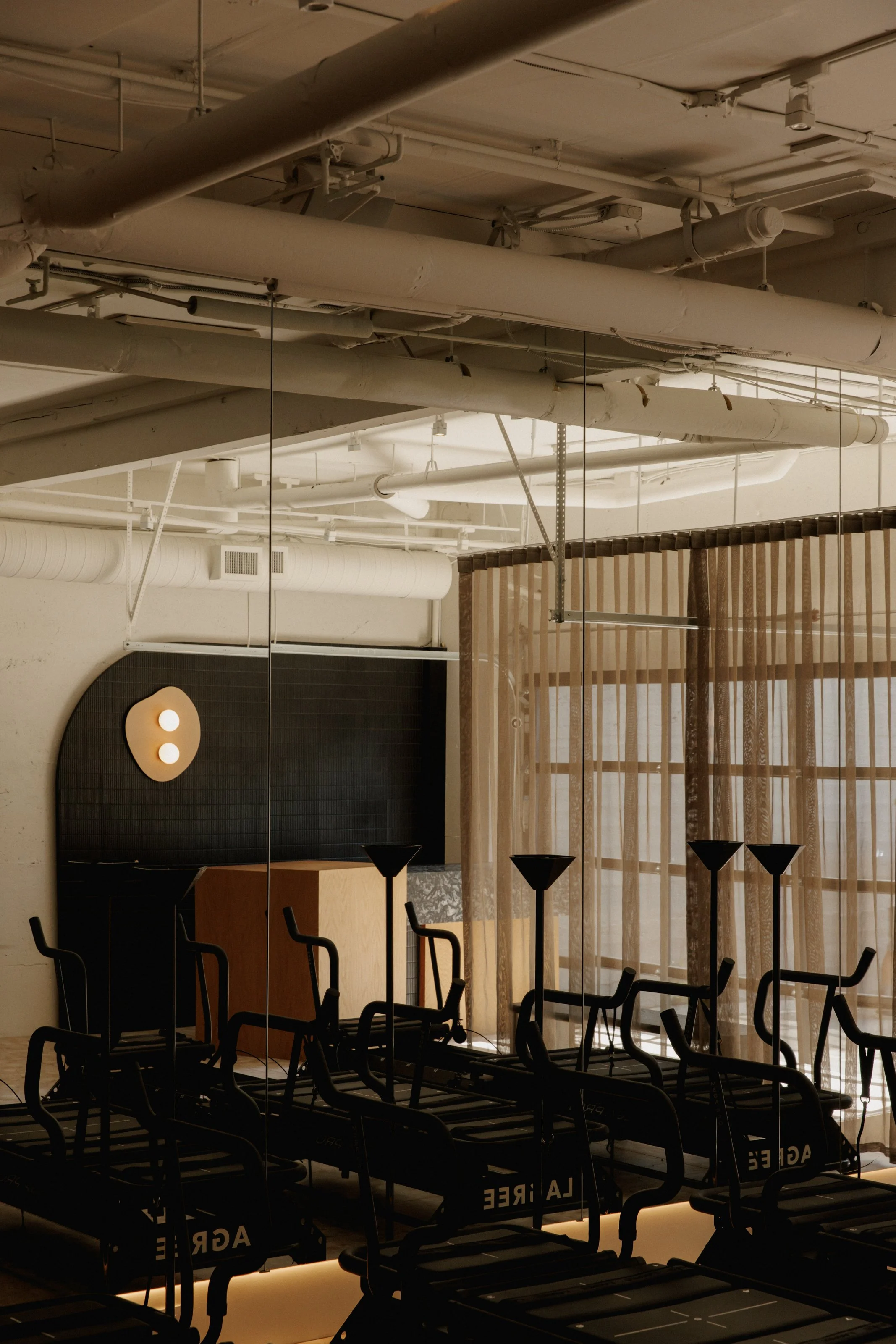 Reformer pilates studio with sheer beige curtains separating the space.