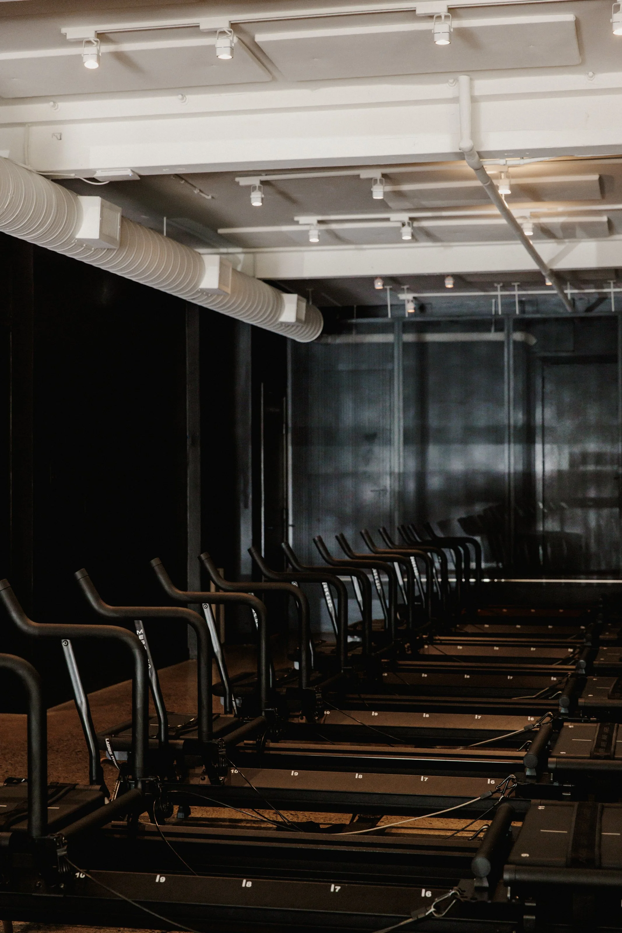 Reformer pilates set in a black room with white paneled ceiling.