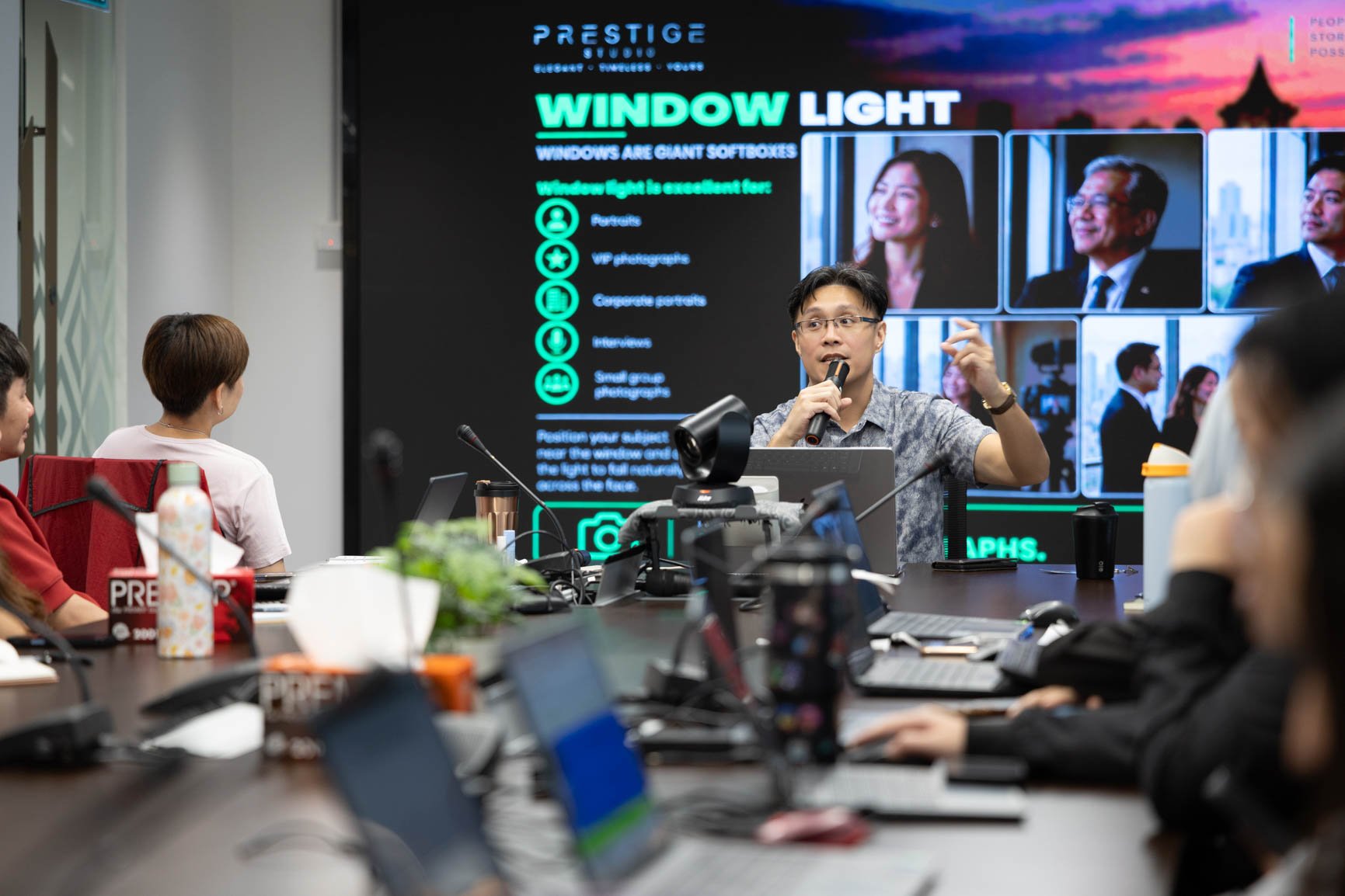 Smartphone photography trainer teaching corporate participants how to use window light during a hands-on workshop in Sarawak.