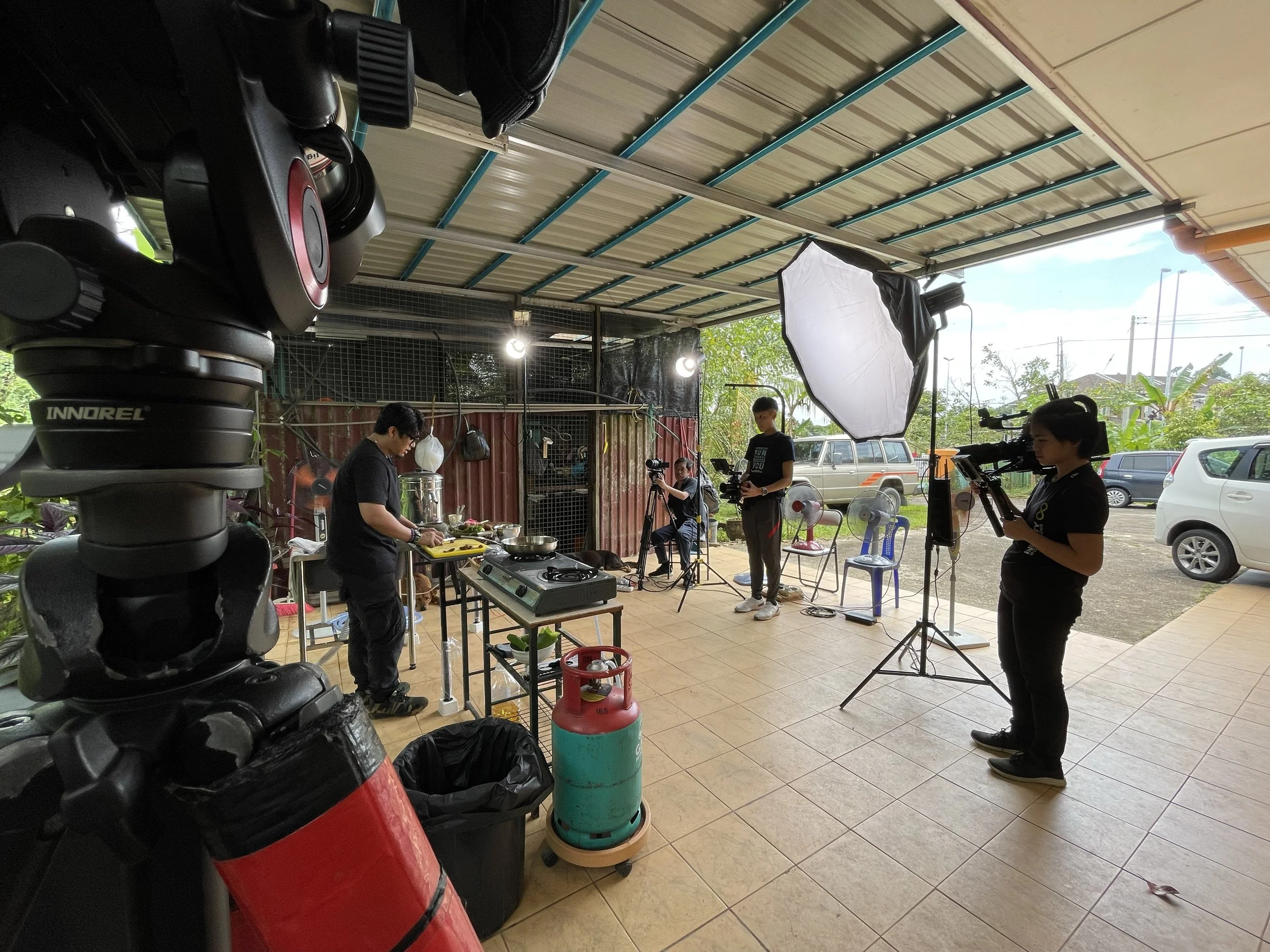 Behind-the-scenes production of a YouTube cooking series, showing the full filming setup with lighting, crew, and cooking station.