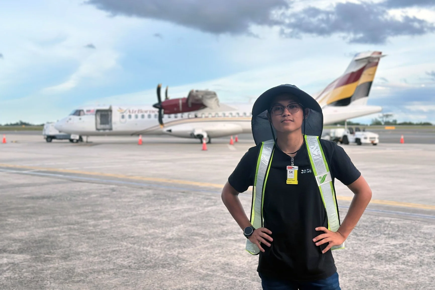 Video production team member standing on airport runway during aviation filming in Sarawak (Air Borneo)