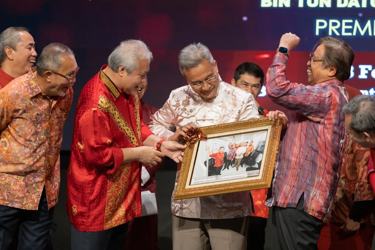 Corporate award presentation ceremony in Kuching featuring a framed photograph taken earlier the same day, presented moments later during the event.