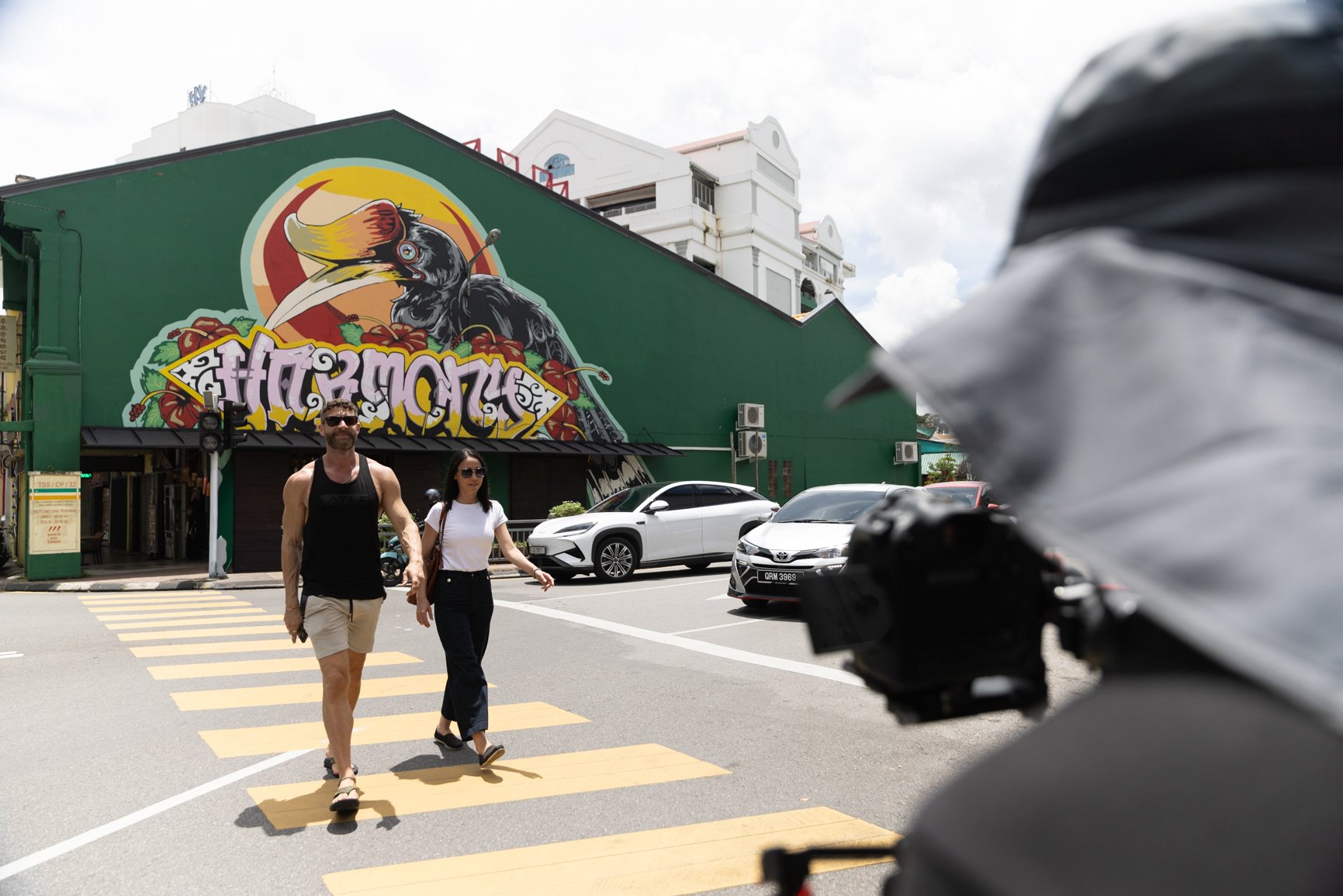 Behind the scenes of a commercial shoot for Sarawak Tourism Board with crew filming talents crossing the street in Kuching
