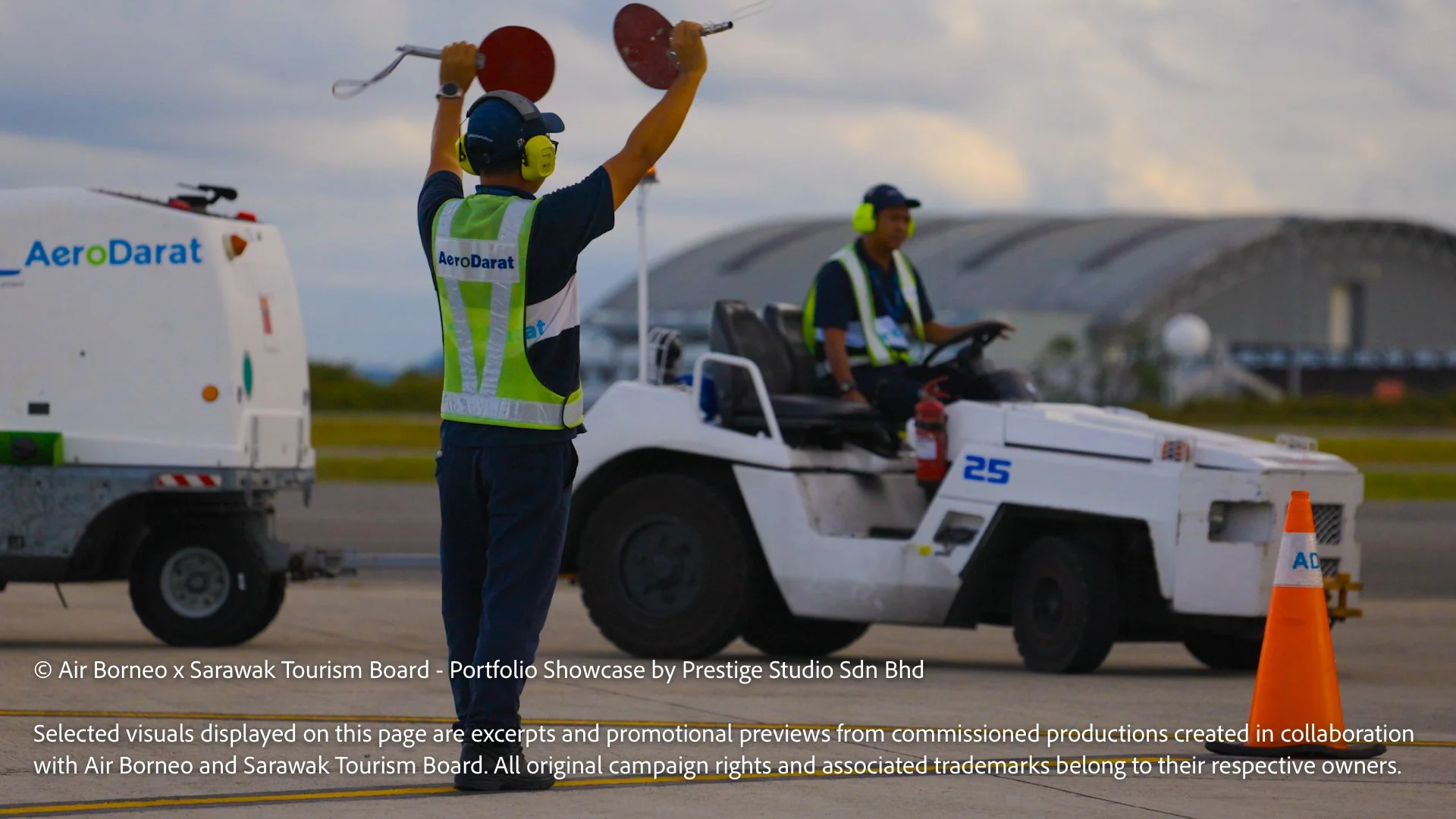 Airport marshal guiding aircraft ground movement on the runway beside support vehicles