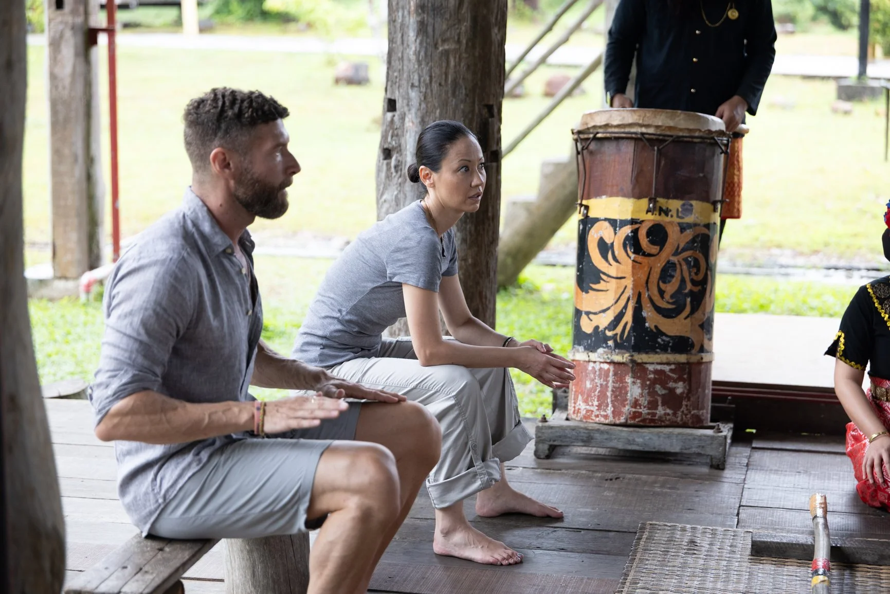 Behind the scenes of a Sarawak Tourism commercial showing visitors learning traditional drum music in a cultural village