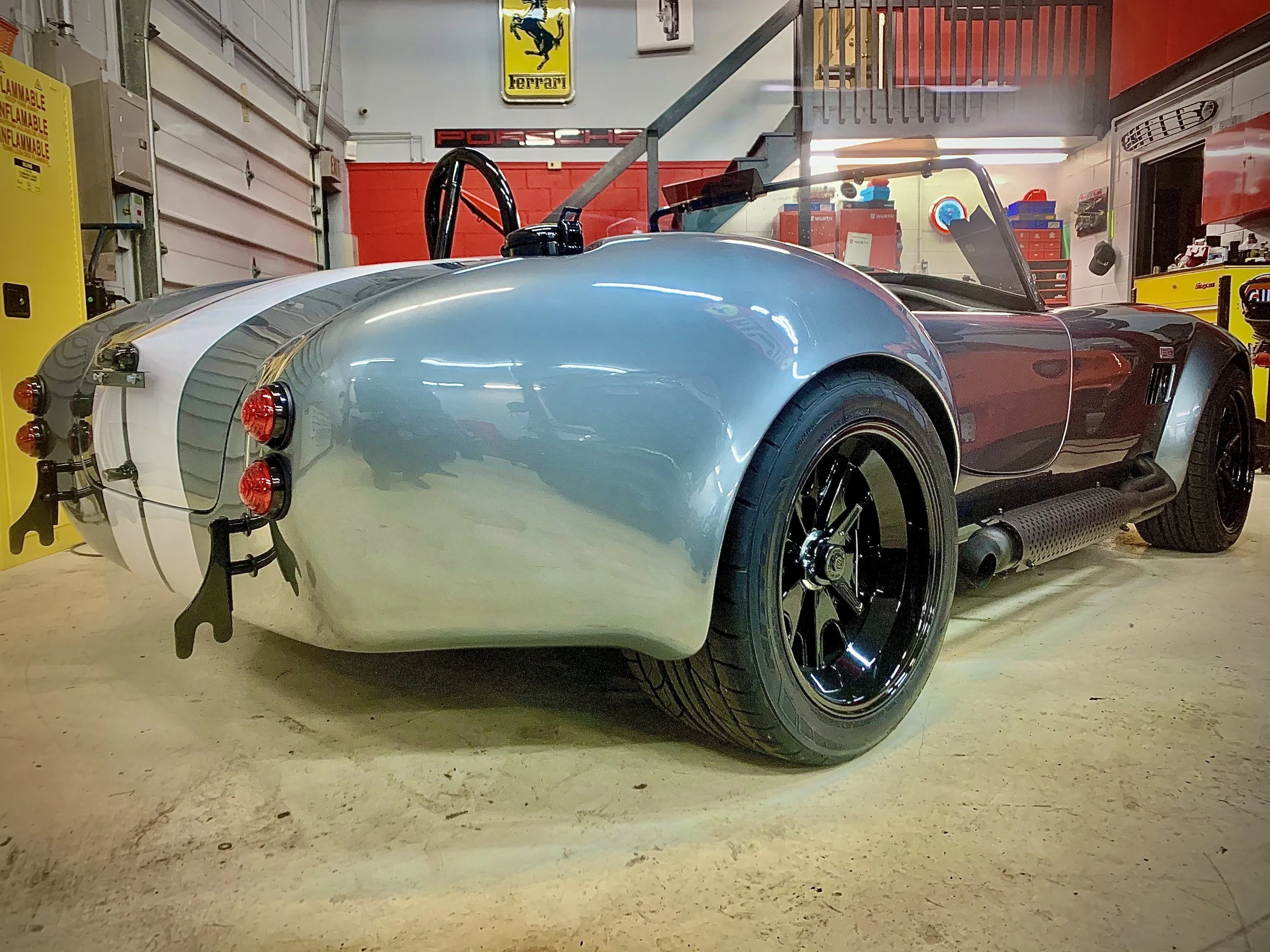 A Shelby Cobra replica sits patiently amongst several Ferraris