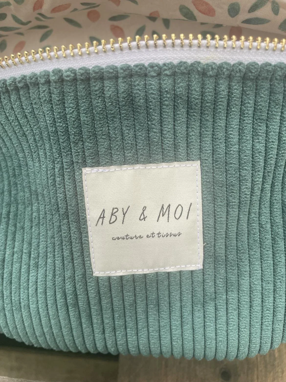 Étiquette avec le texte 'ABY & MOI couture et tissus' cousue sur un tissu en relief vert.