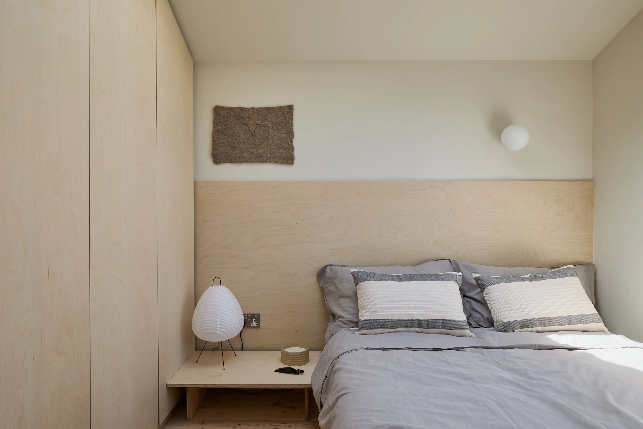 Bedroom at Norwood House, with timber wardrobes, a matching headboard, grey bedding and a white bedside lamp.