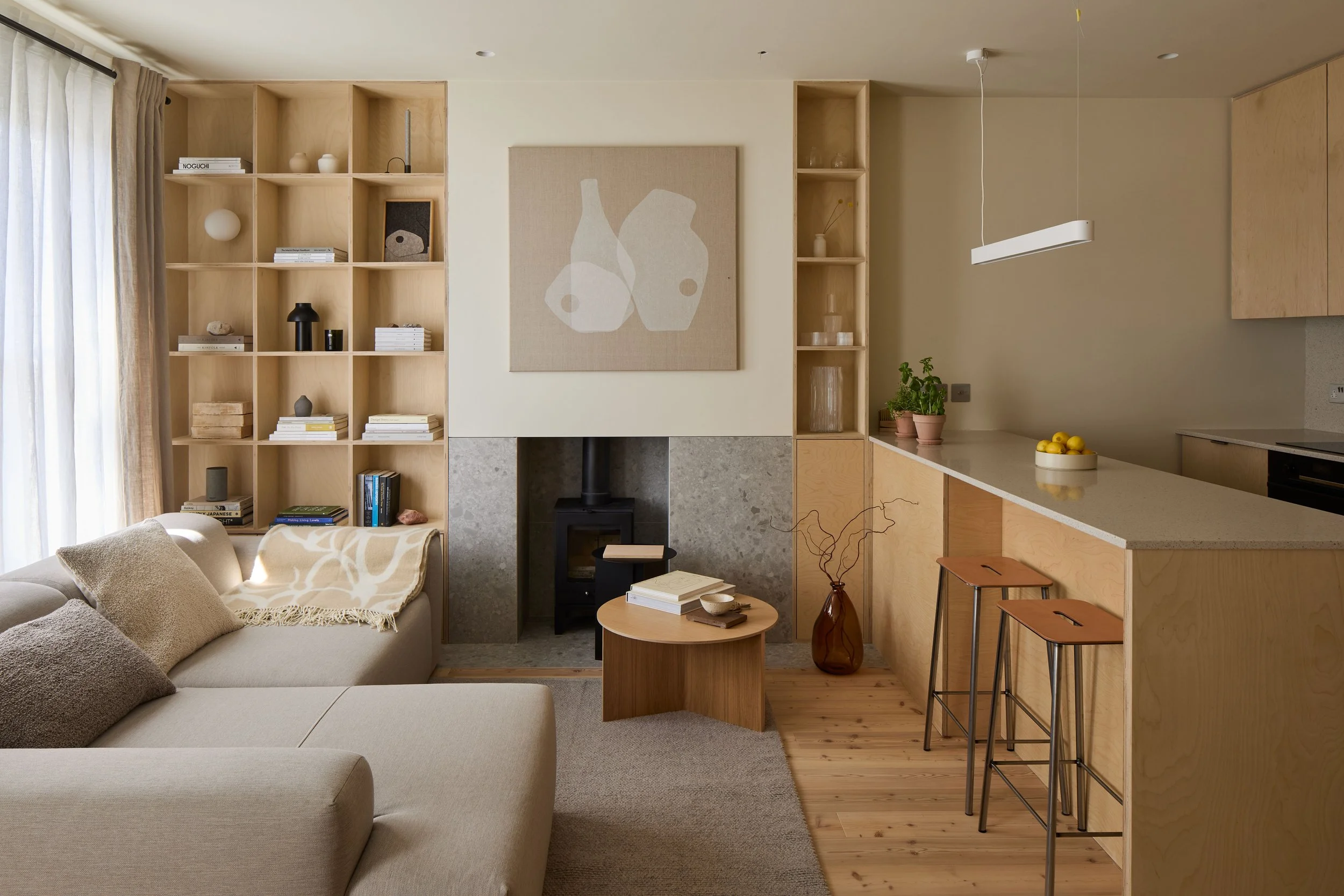Renovated open-plan kitchen and living room in Norwood, South London, with timber cabinetry, a breakfast bar and a wood-burning stove.
