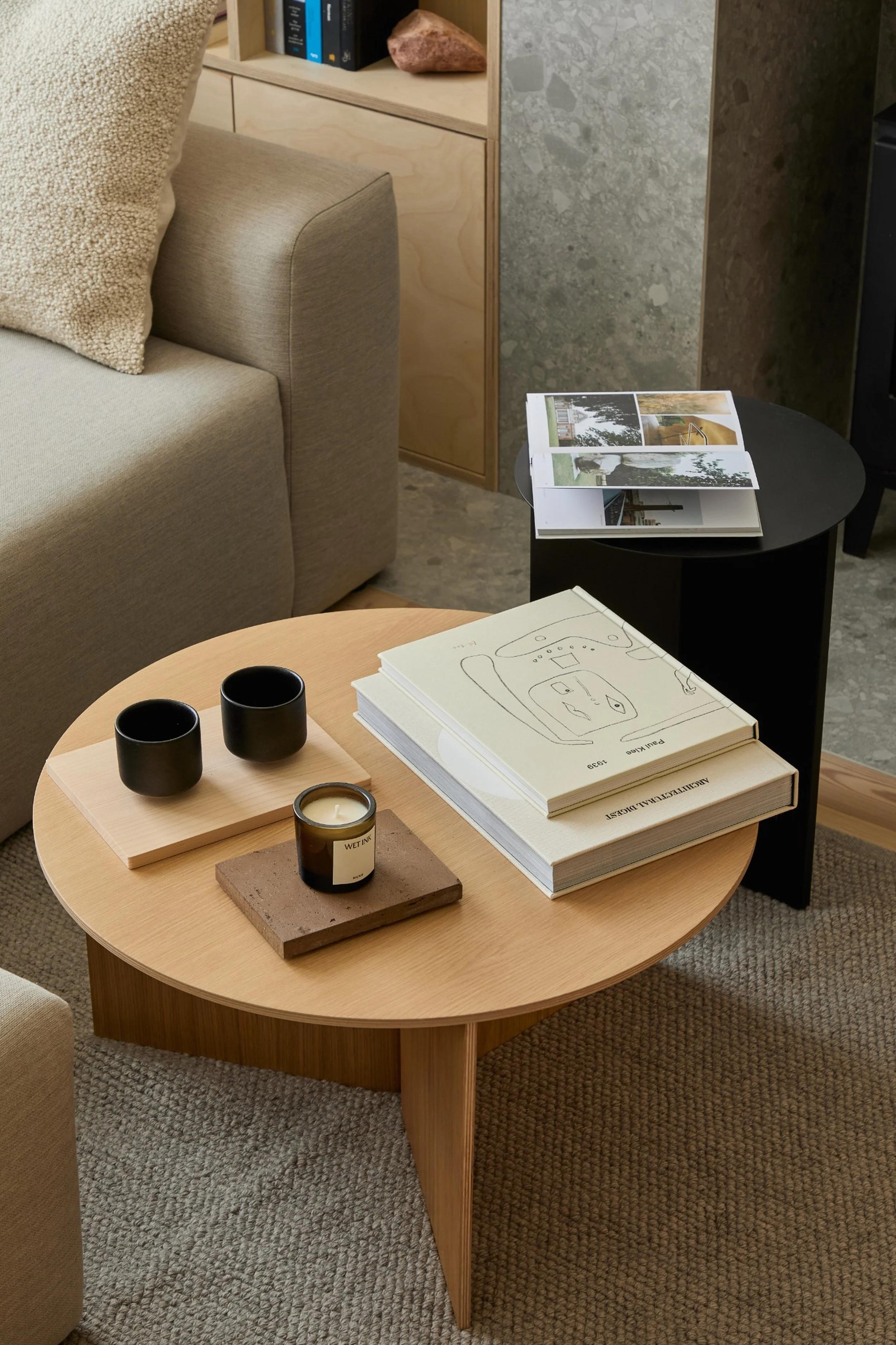 Living room detail at Norwood House, with a round timber coffee table, books and cups beside a neutral sofa.