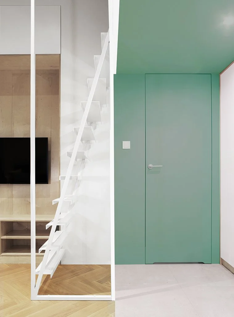 Interior details at Apartment 30: a white mezzanine staircase beside timber panelling and a flush mint-green door.