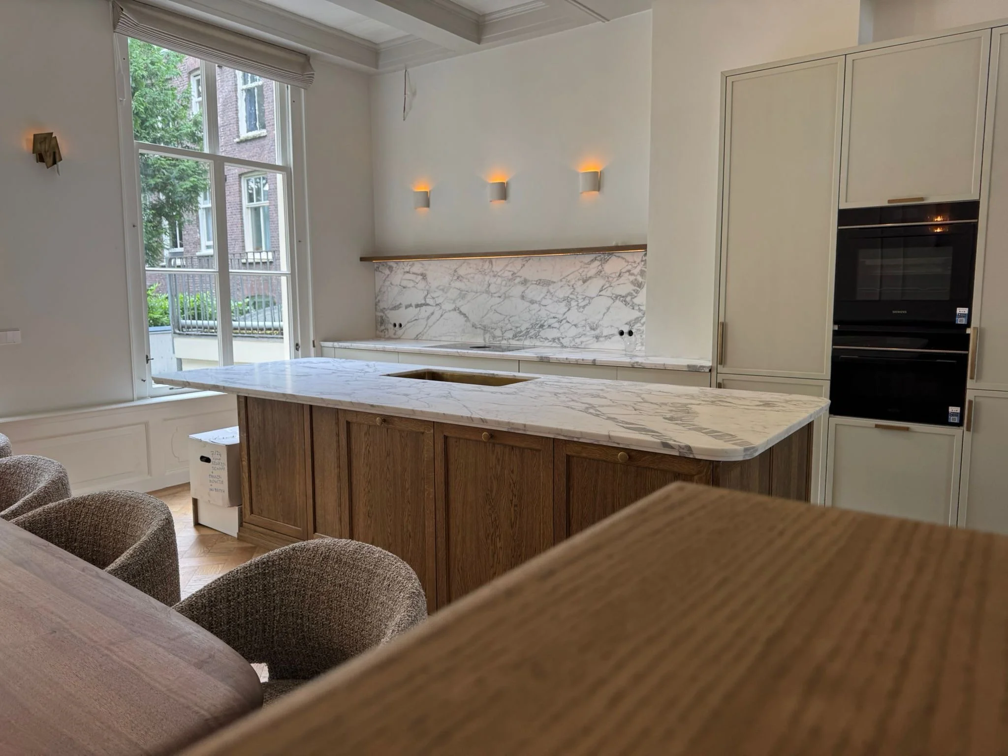 Maatwerk keuken in Amsterdam met eiken kookeiland en gespoten kastenwand