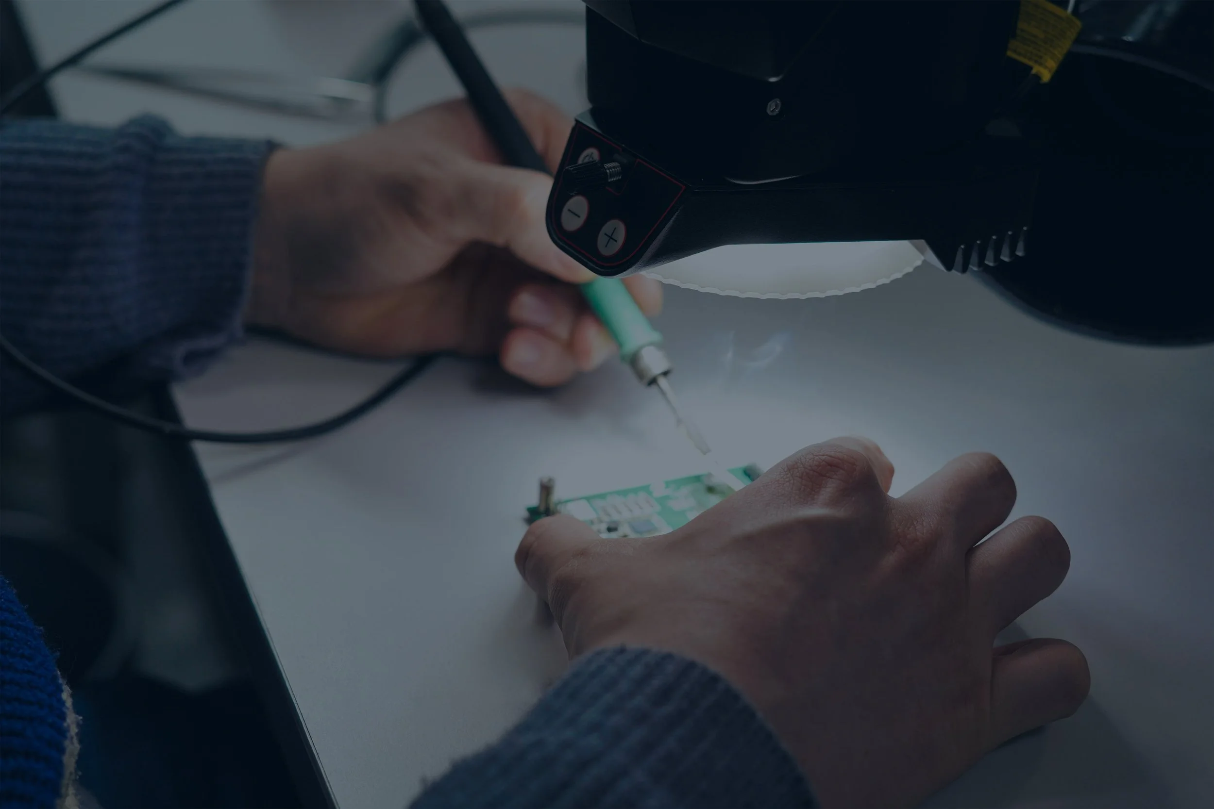 Two male employees of Munich Electrification discussing hardware features of a circuit board for battery management systems.
