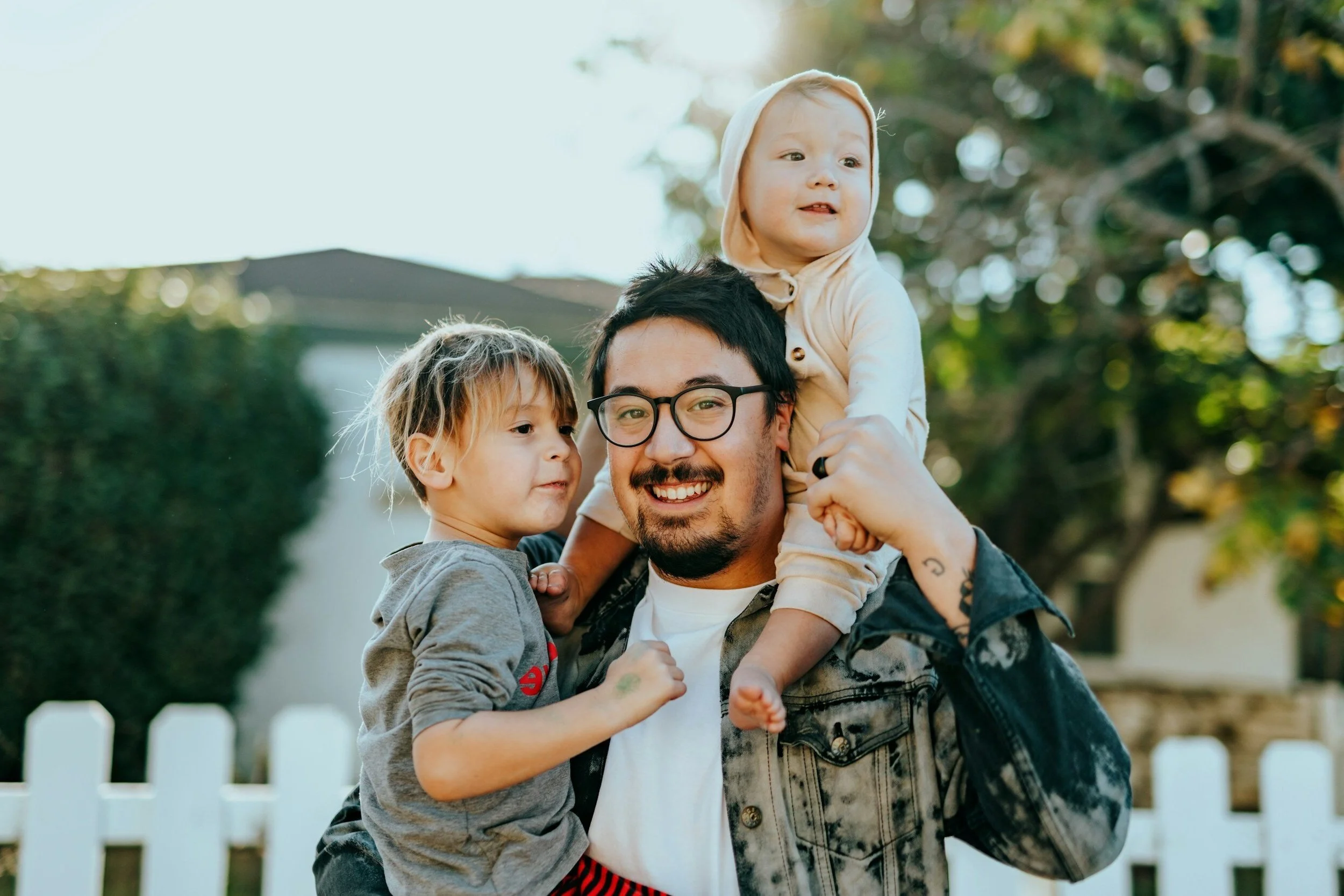 Parent holding two young children outdoors