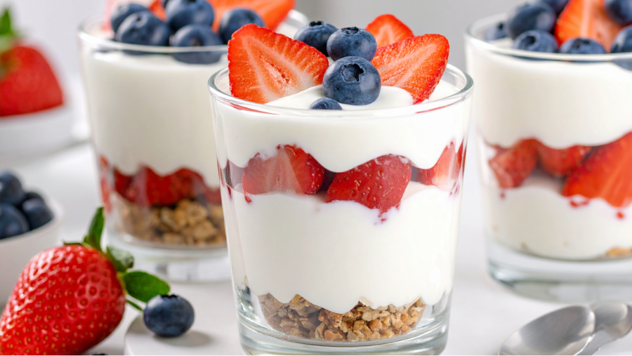 Yogurt parfaits with strawberries, blueberries, and other toppings set up for a breakfast-themed birthday party