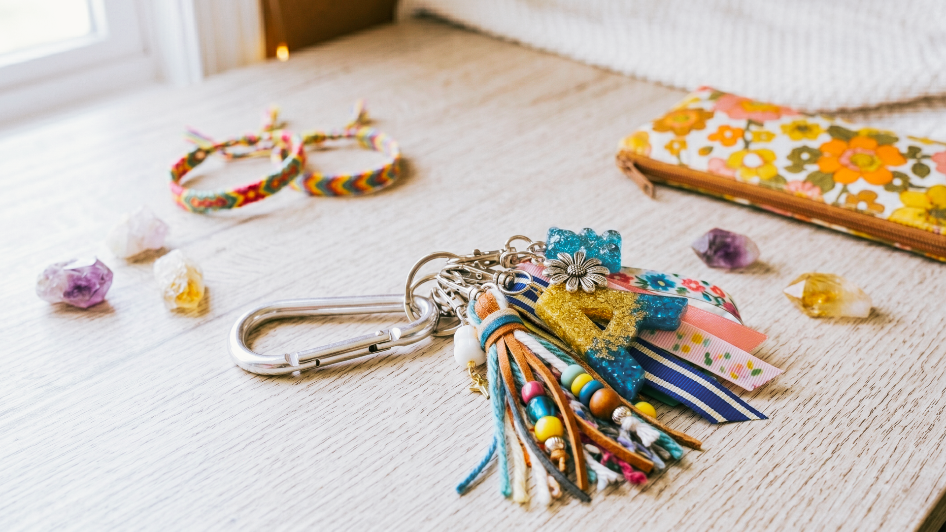 Charm bar party setup for tweens with a carabiner featuring tassles and charms. There are additional accents on the table and friendship bracelets in the background.