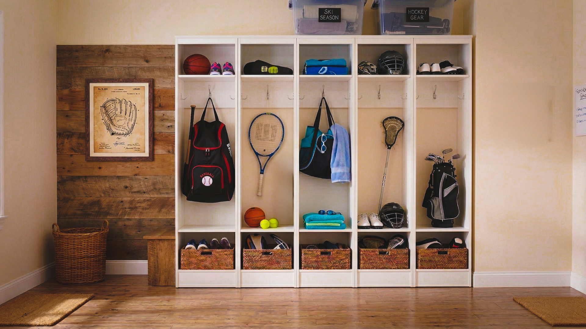 A clean, organized mudroom with locker-style storage for kids' sports equipment. Each cubby has gear for different sports tucked away neatly.
