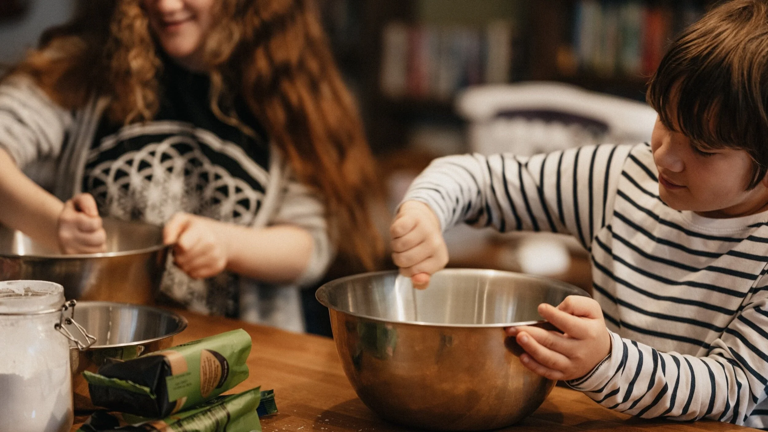 A young boy and girl stirring ingredients in mixing bowls.