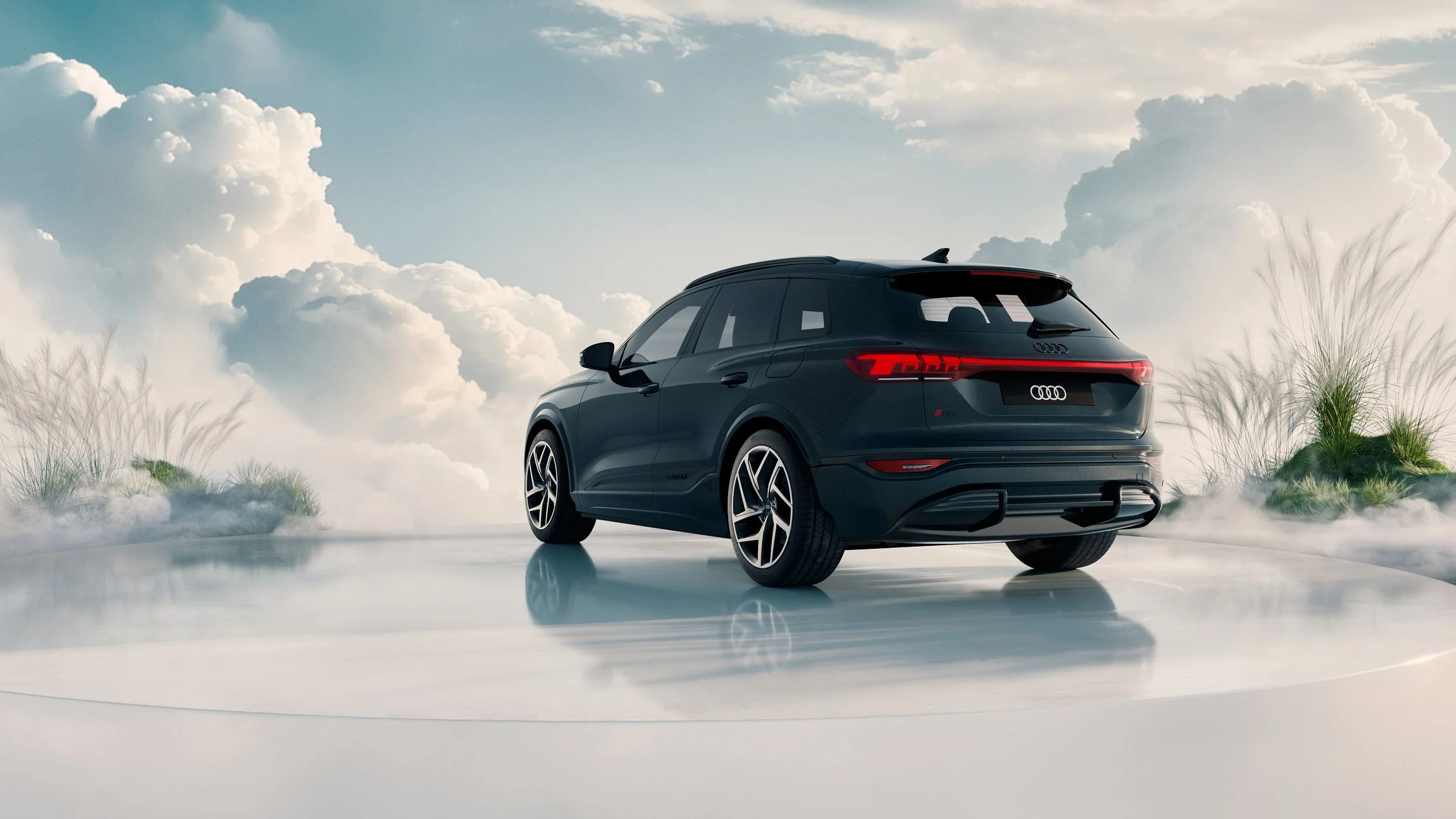 A sleek black Audi SUV parked on a foggy, reflective surface outdoors with a cloudy sky and tall grass in the background.