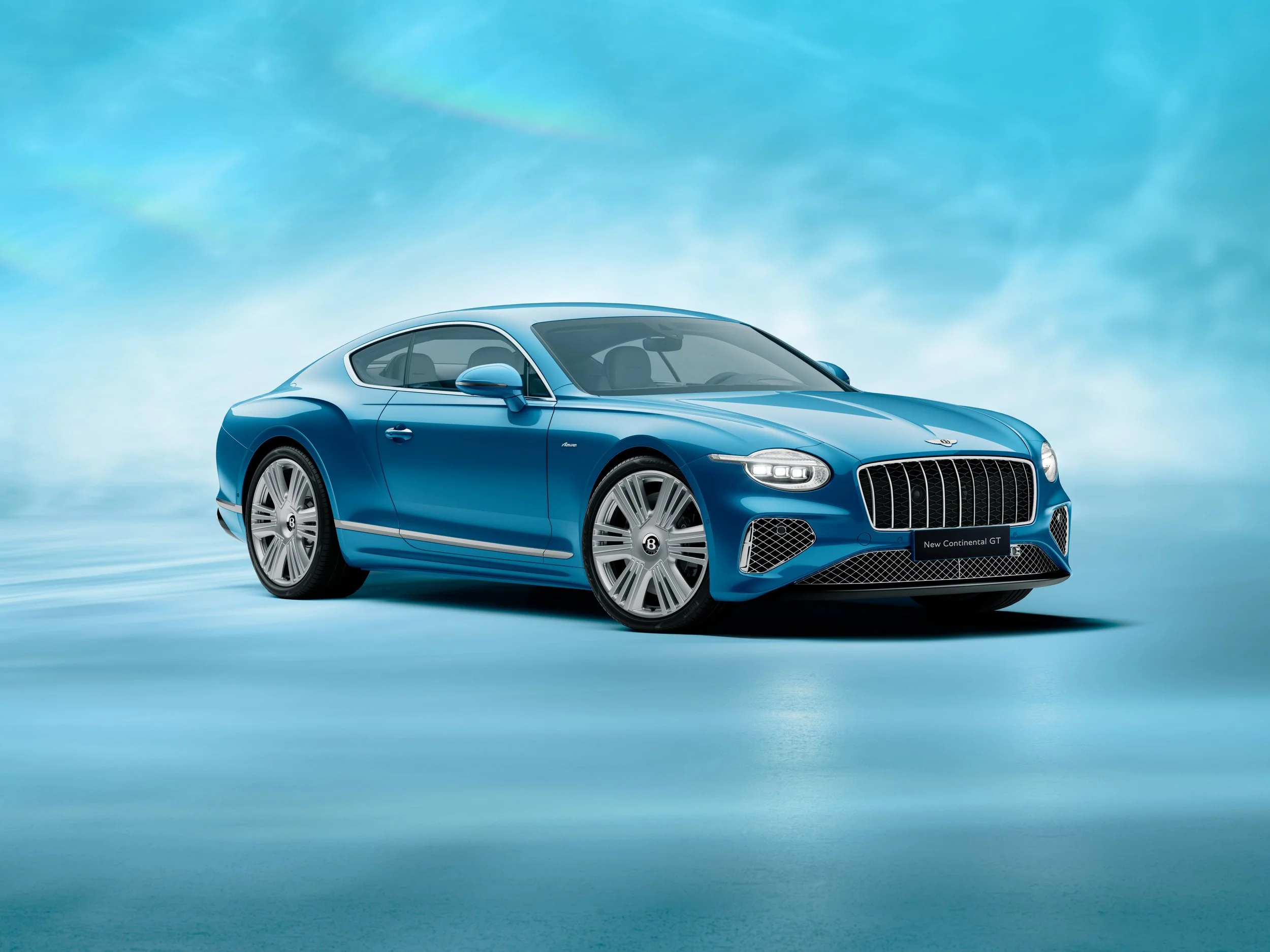 A blue luxury coupe car parked on a reflective surface with a cloudy blue sky in the background.