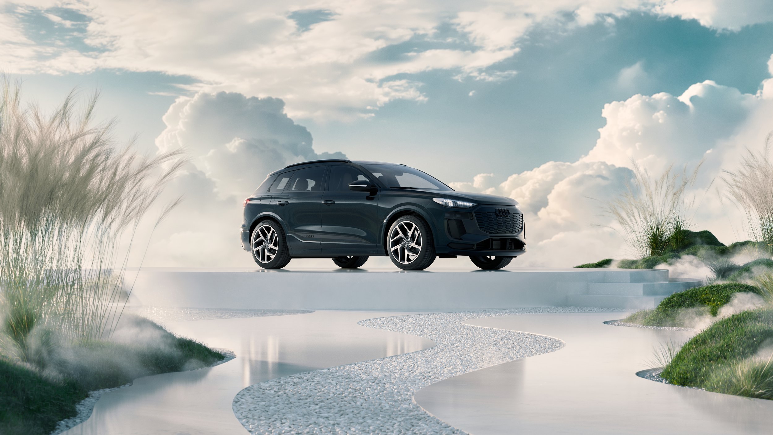 A modern black SUV parked on a white platform outdoors under a partly cloudy sky, with grasses and rocks nearby.