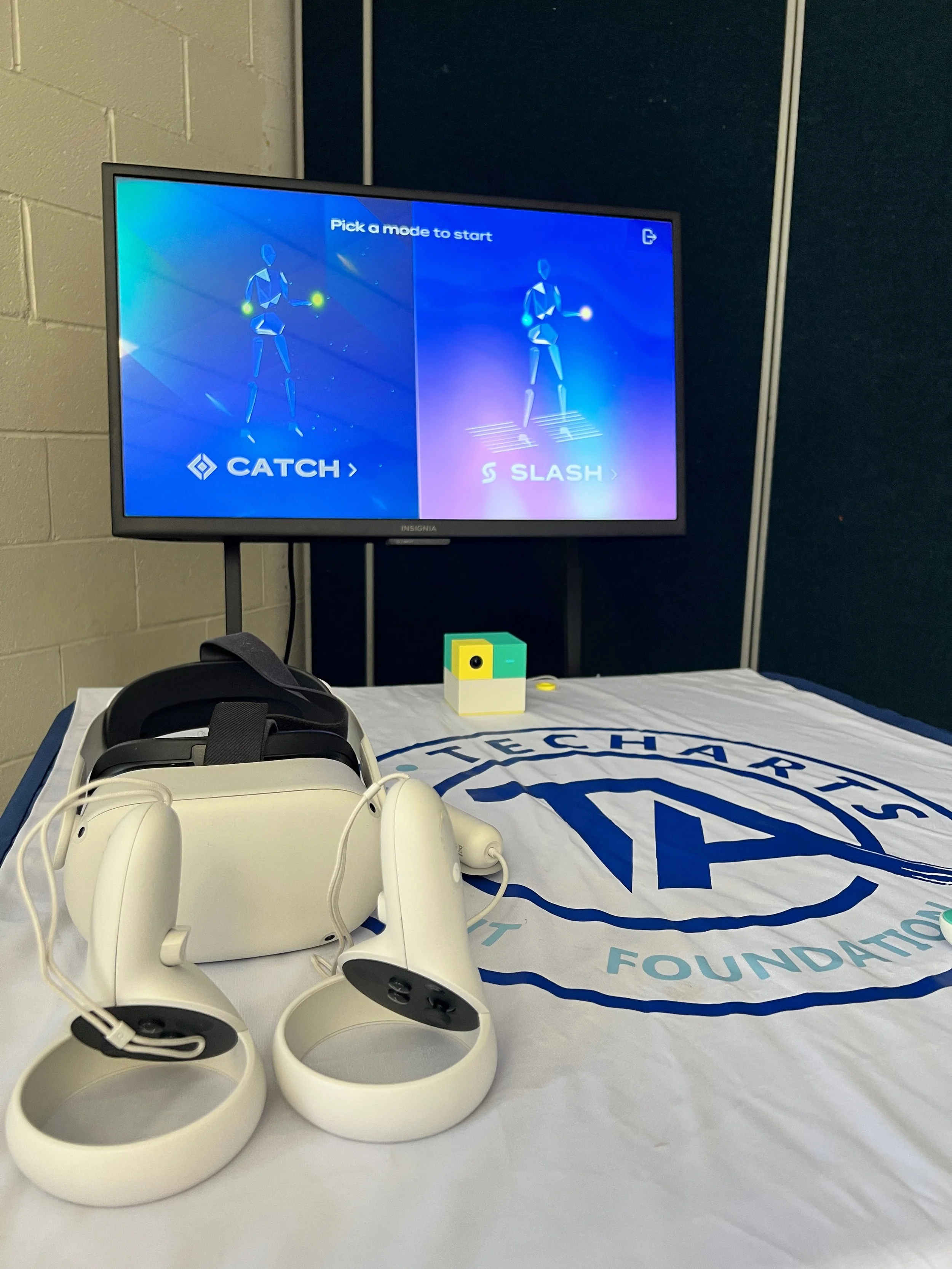 Home office setup with desktop computer, laptop, digital drawing tablet, smartphone, desk lamp, and decorative items in a bright room.