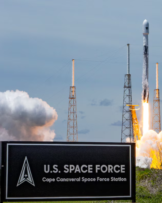 Rocket launching from Cape Canaveral Space Force Station, with smoke and flames, and a sign for U.S. Space Force