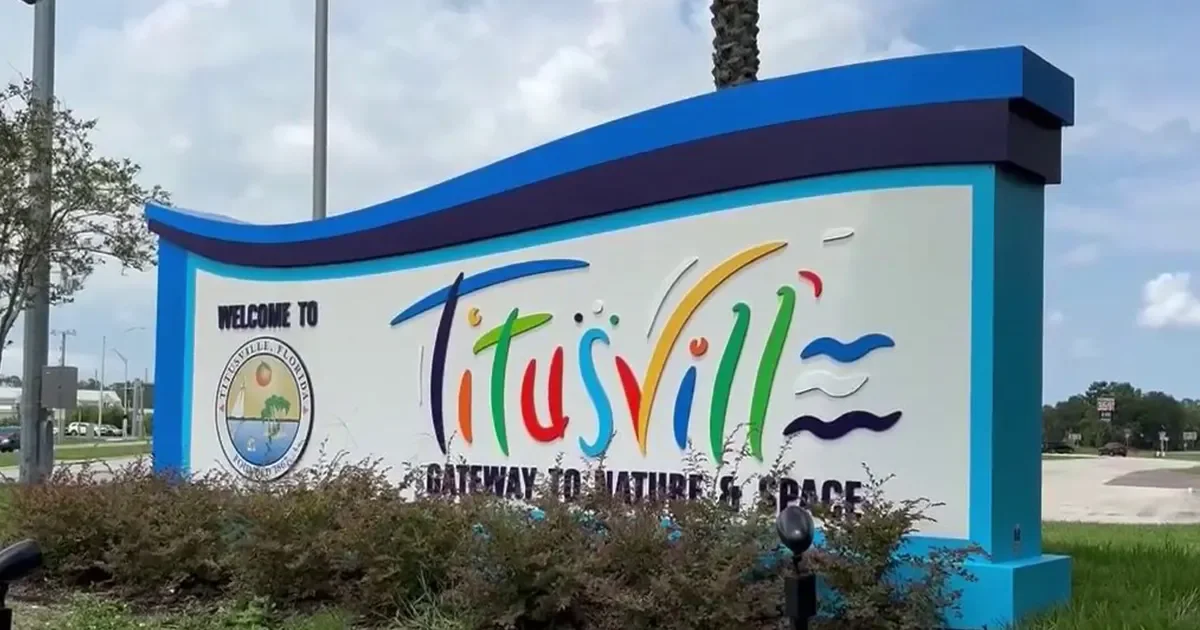 Colorful welcome sign for Titusville, Florida, stating 'Gateway to Nature & Space' with graphics of waves and a bird.