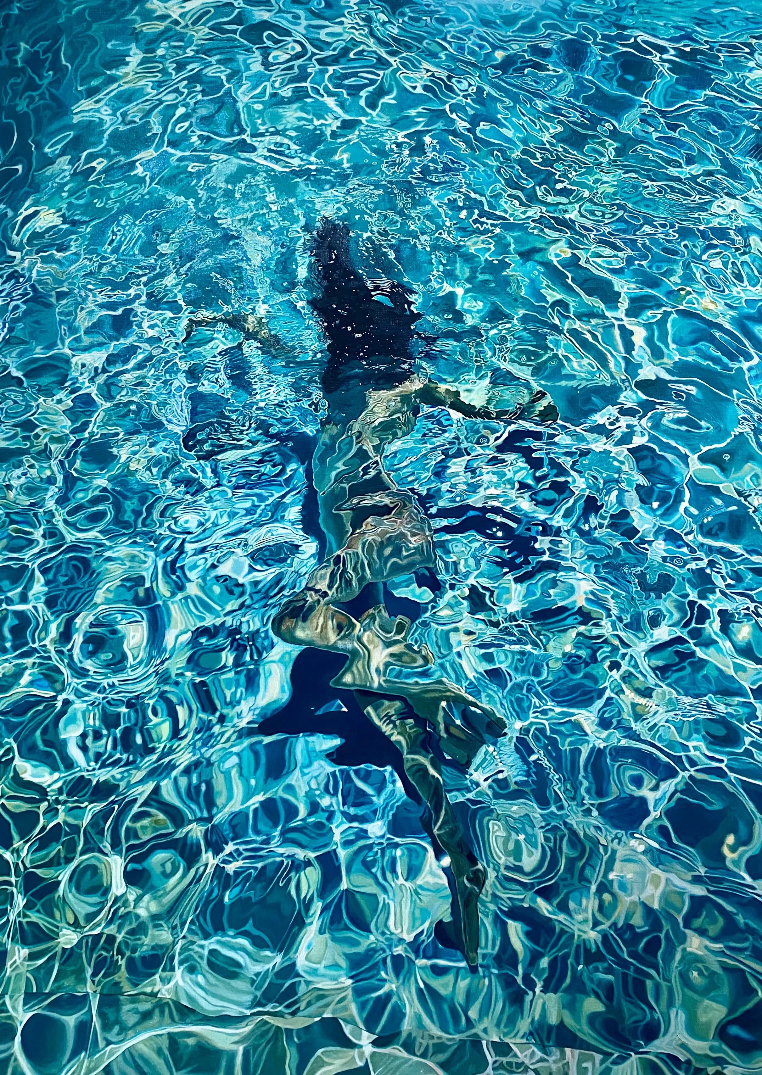 Person swimming underwater in a pool with clear blue water and sunlight reflections.
