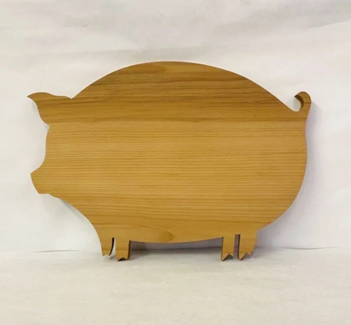 Wooden pig-shaped decoration or cutting board with a natural wood finish, positioned against a plain white background.