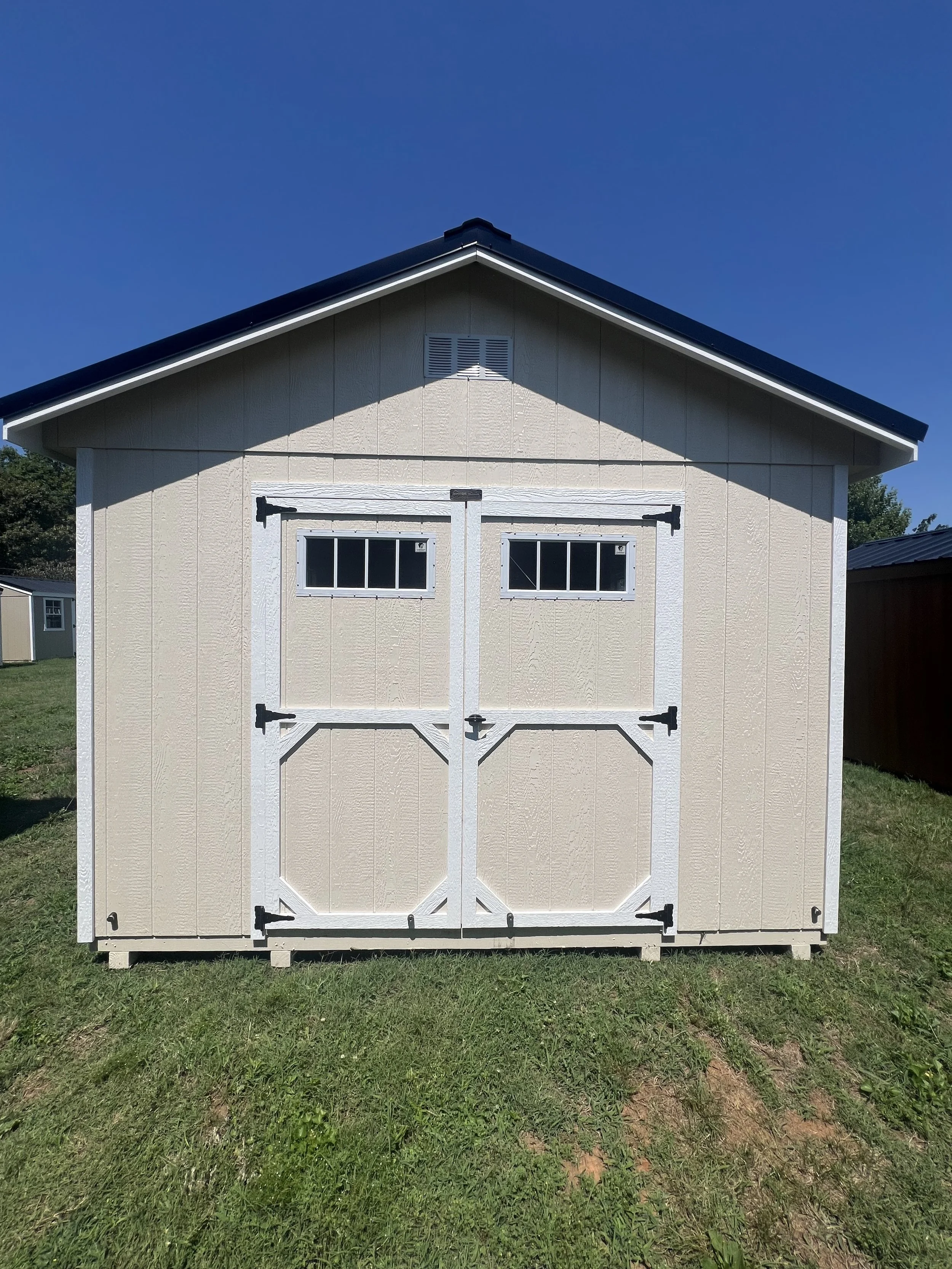 an almond and black portable storage shed with windows and double doors.