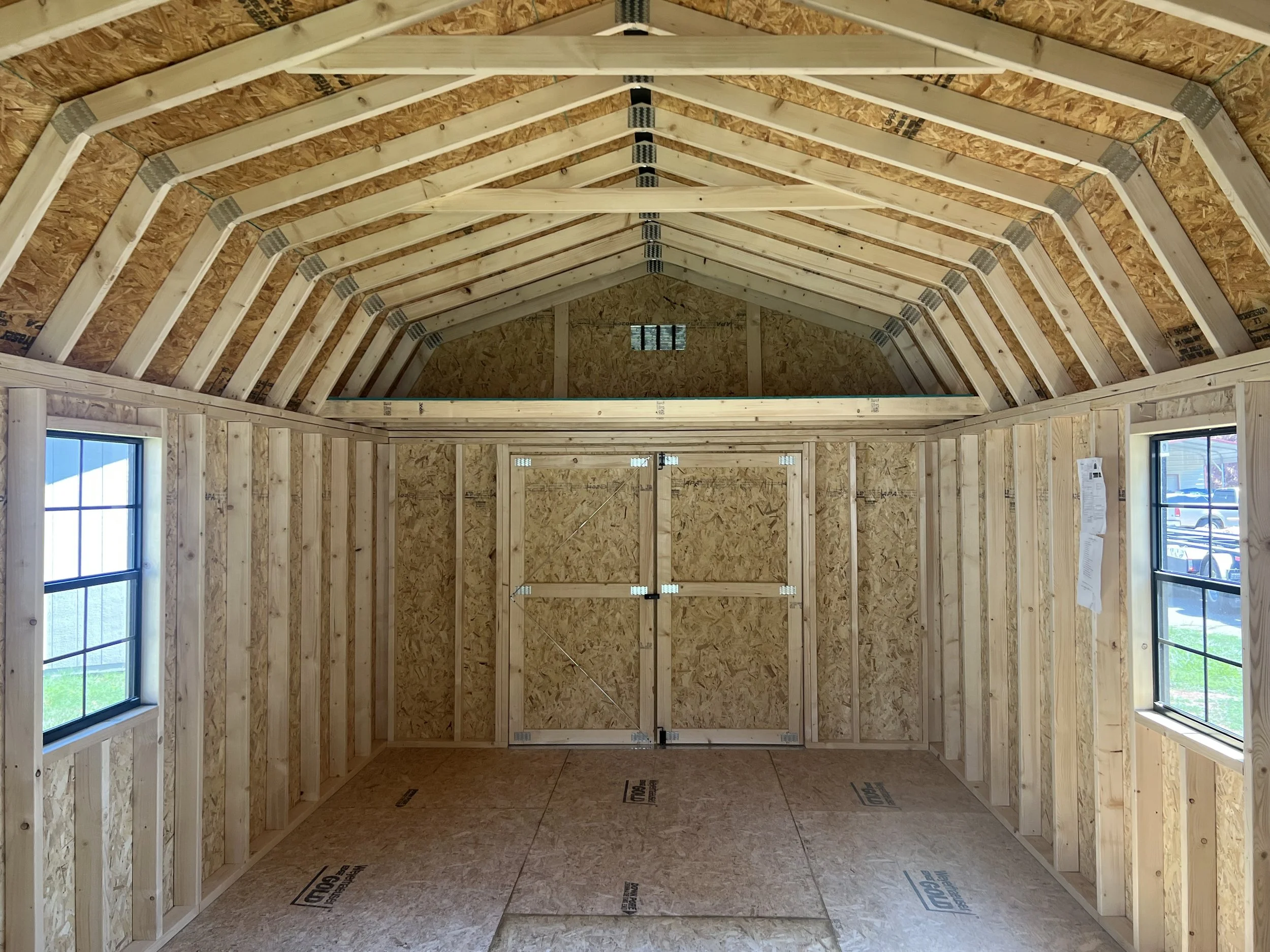 Interior view of an unfinished wooden shed showing the exposed framework and OSB walls.