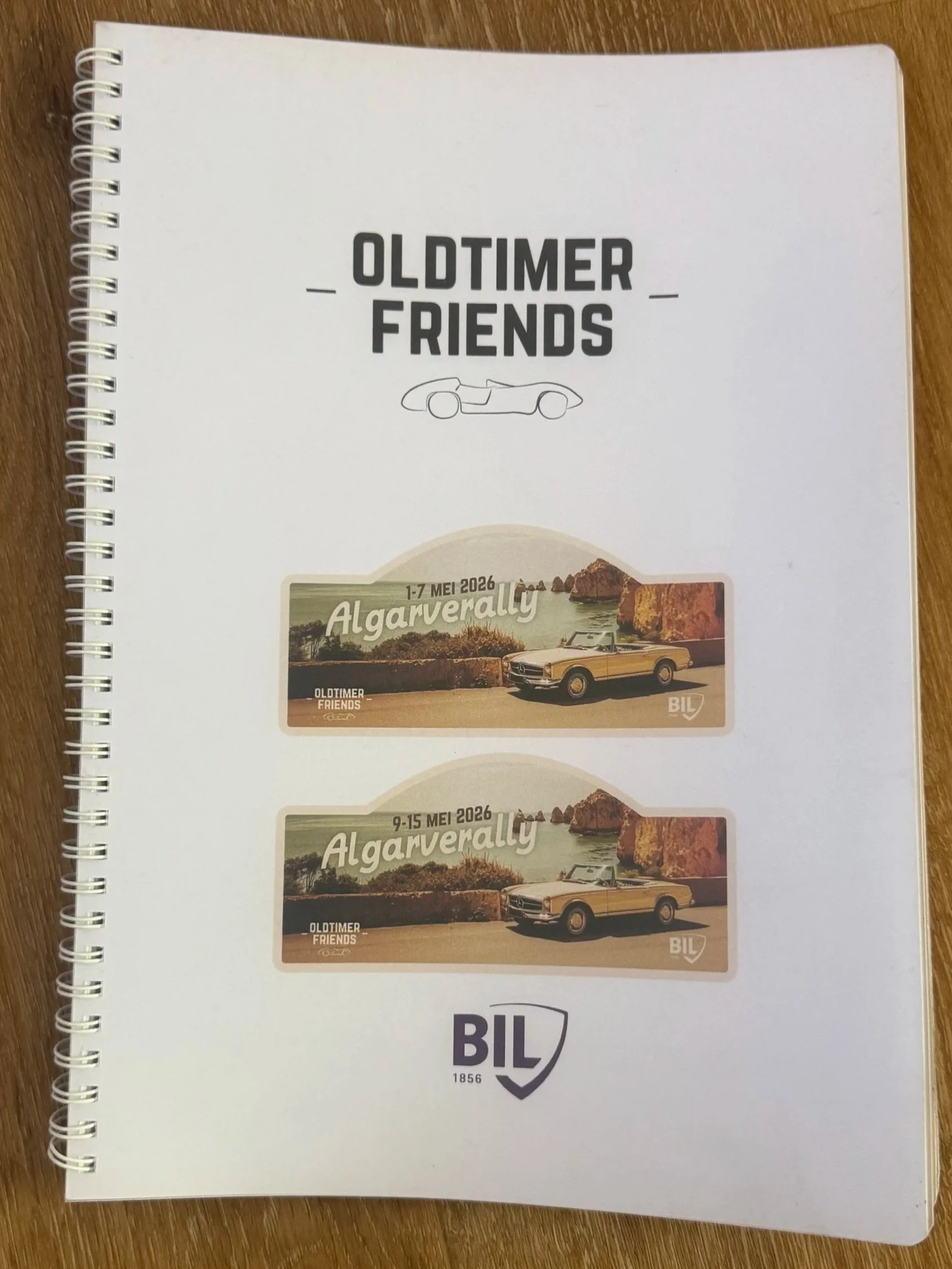 Een boek met de titel 'Oldtimer Friends' en enkele reisadvertenties voor de Algarve, met foto's van klassieke auto's en landschappen.