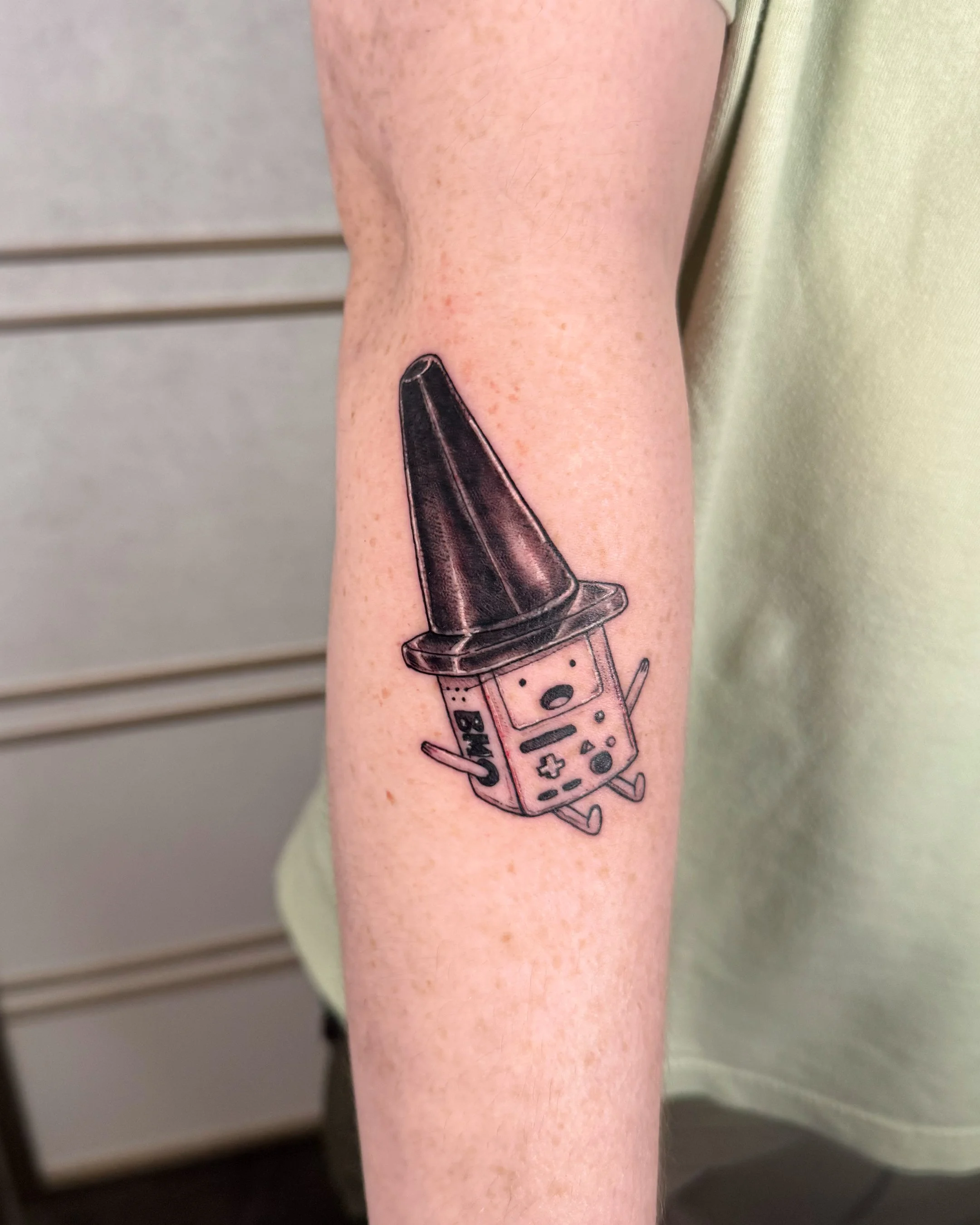 Tattoo of a voting machine with a finger scanner, decorated with small angel wings.