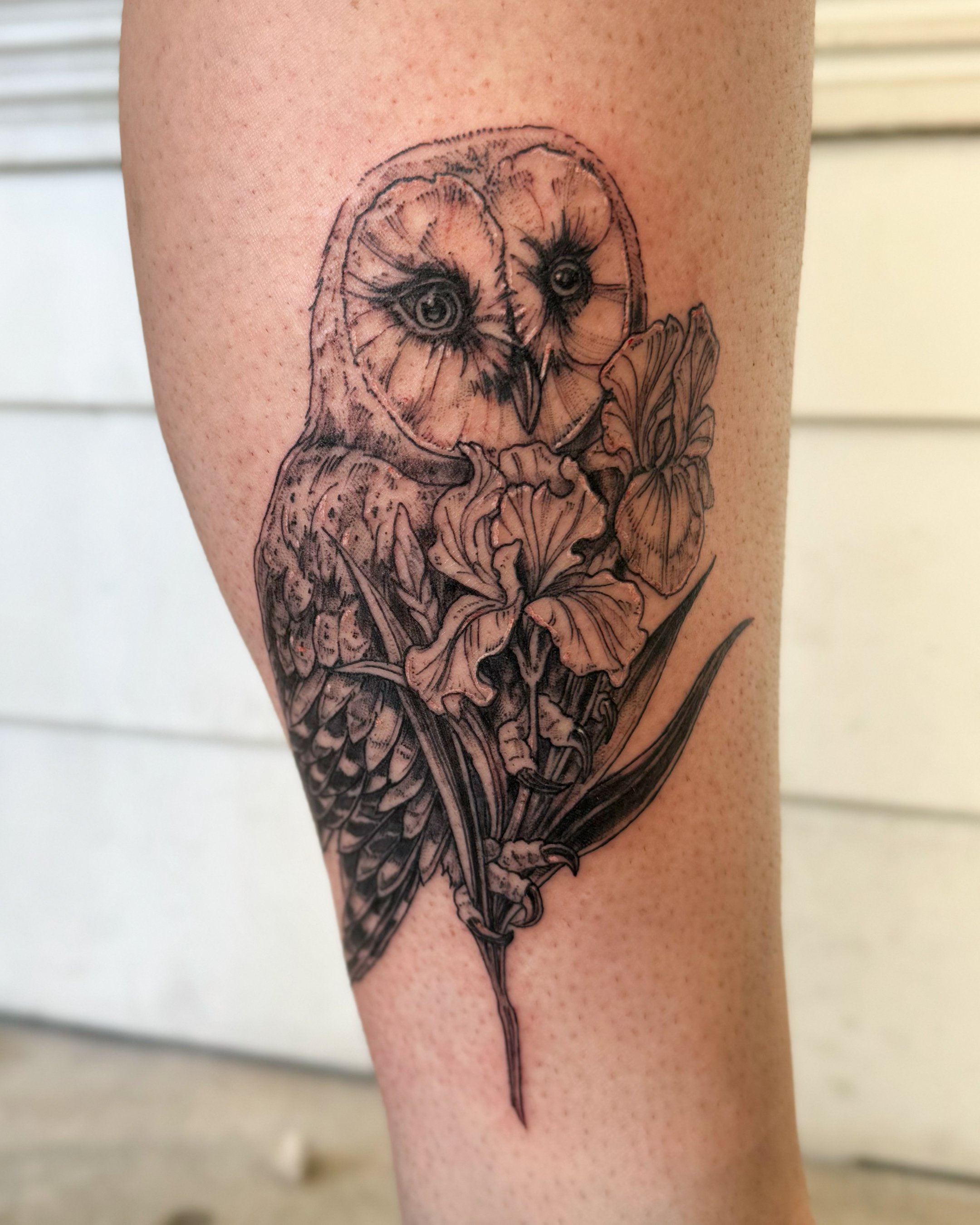 Tattoo of an owl with textured feathers and flowers on a person's skin.