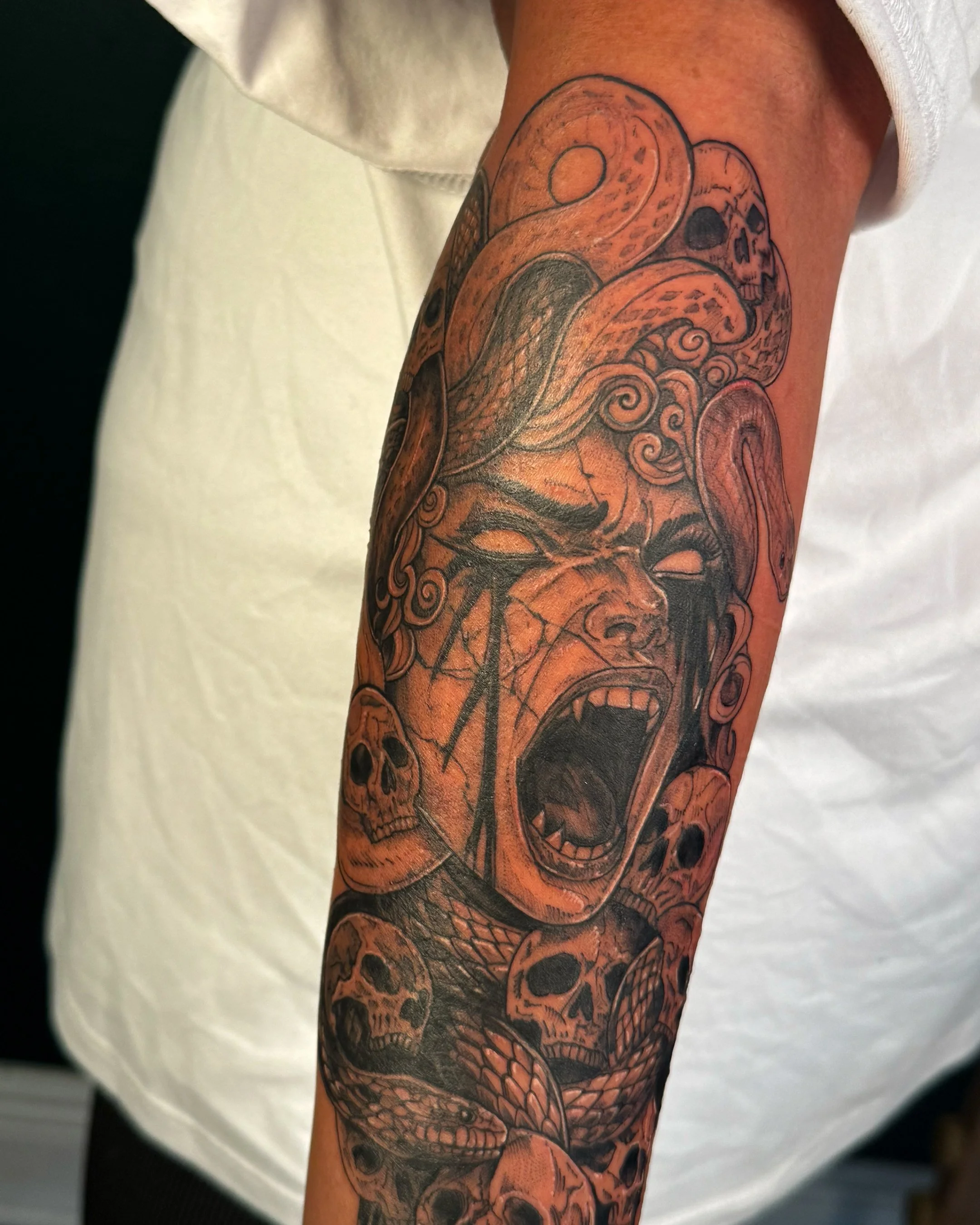Tattoo of a dragon with a skull on a person's arm.