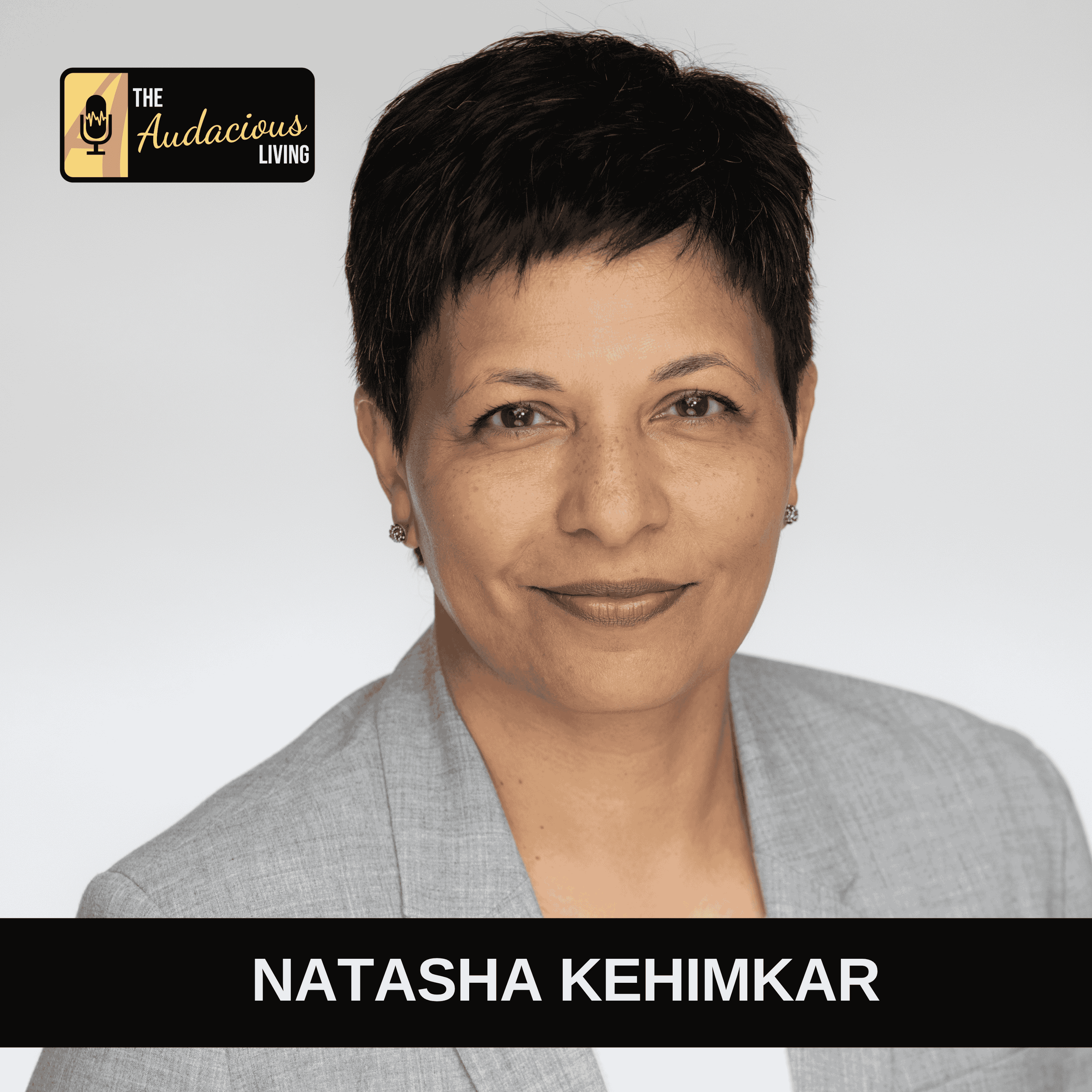 Close-up portrait of Natasha Kehimkar, smiling, wearing a light gray blazer, with short dark hair and earrings, against a plain light background. Logo in the top left corner reads 'The Audacious Living'.