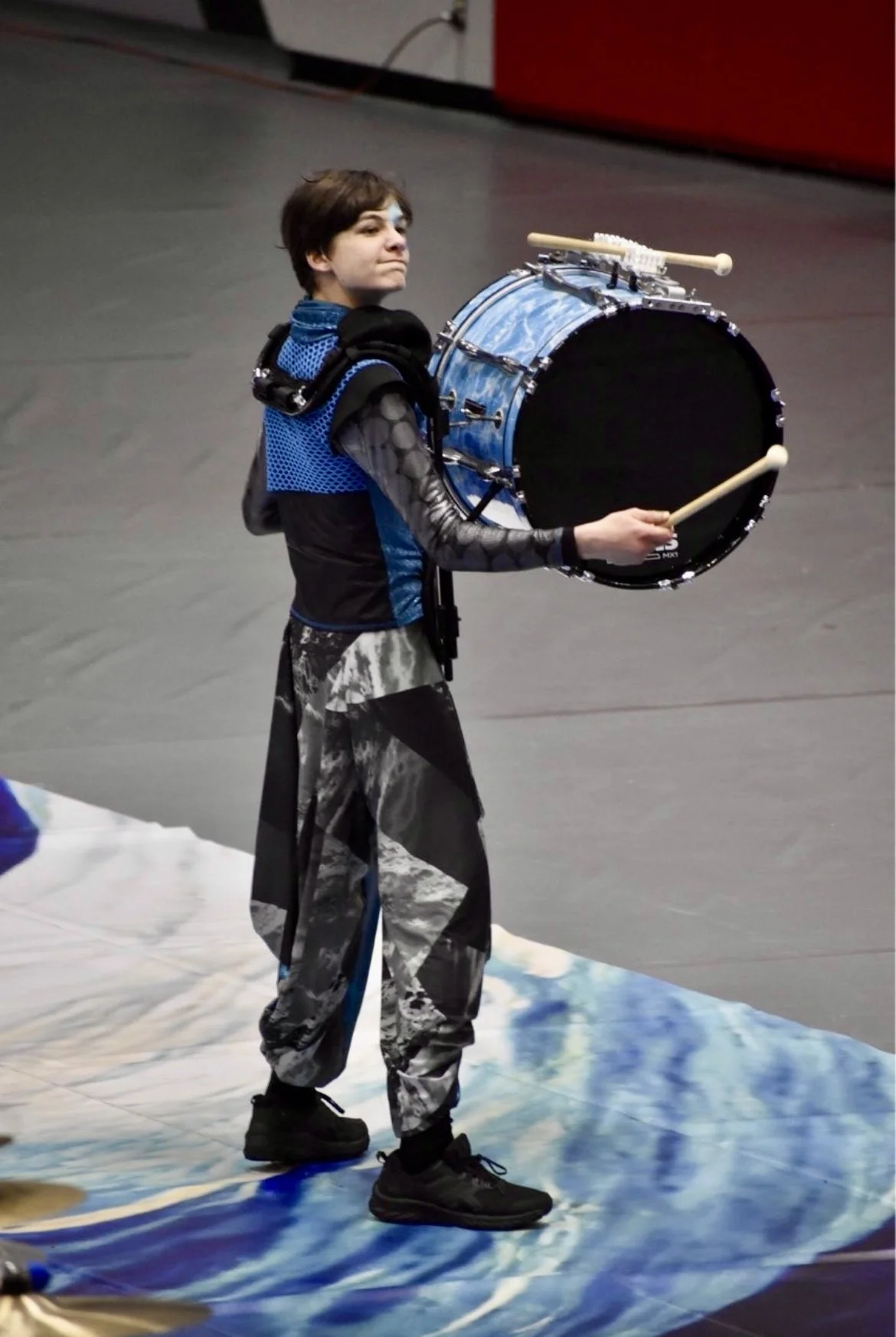 A young person playing a bass drum for winter indoor percussion.