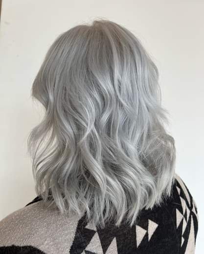 Back view of a woman with shoulder-length, wavy, platinum blonde hair.