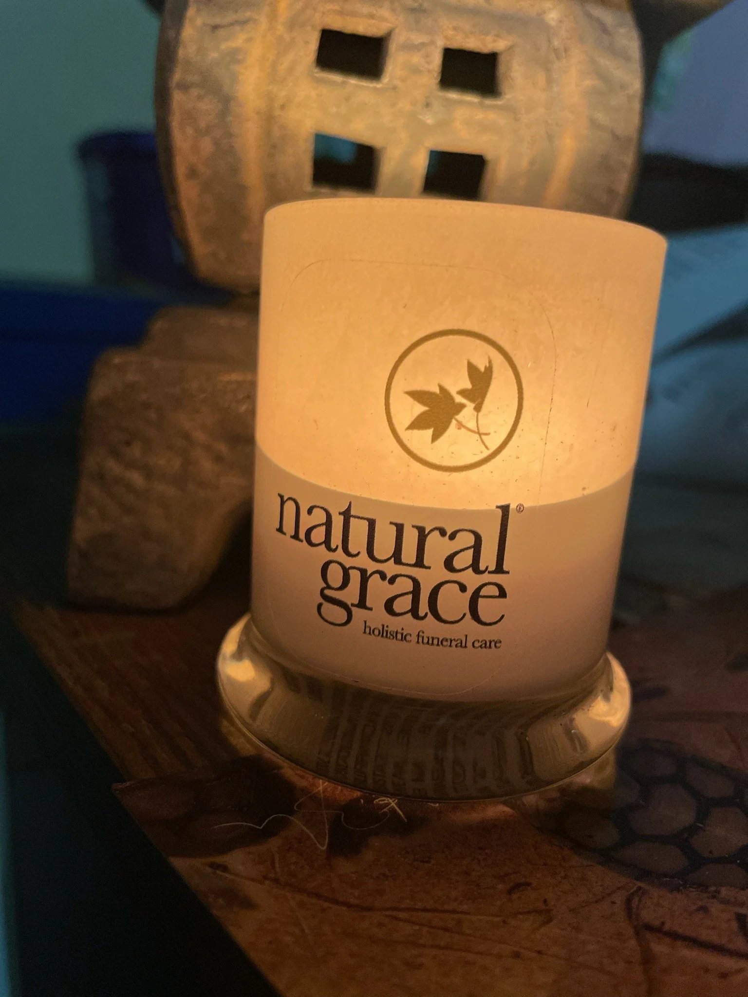 A candle holder with a tattoo design of a leaf on it, placed on a wooden surface.
