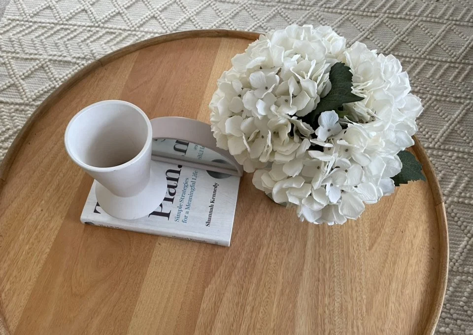 cup of tea, time, sit and meet and greet at a wooden round table holding a white flower arrangement