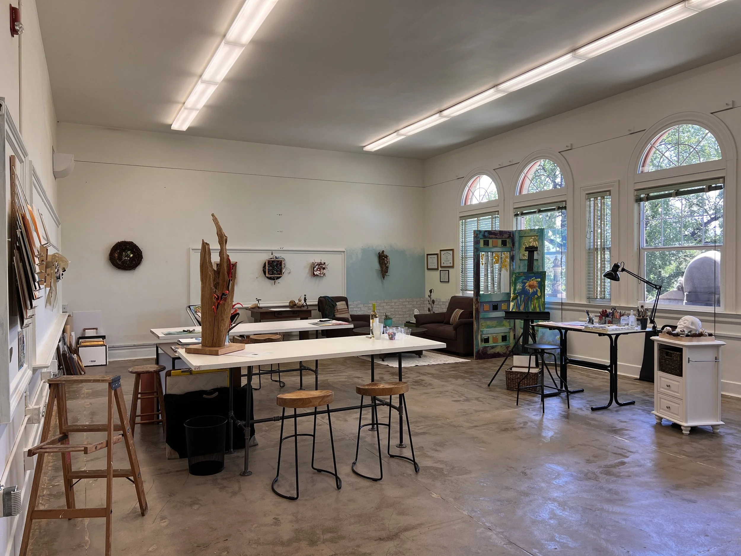 Art studio with tables, stools, supplies, and large windows