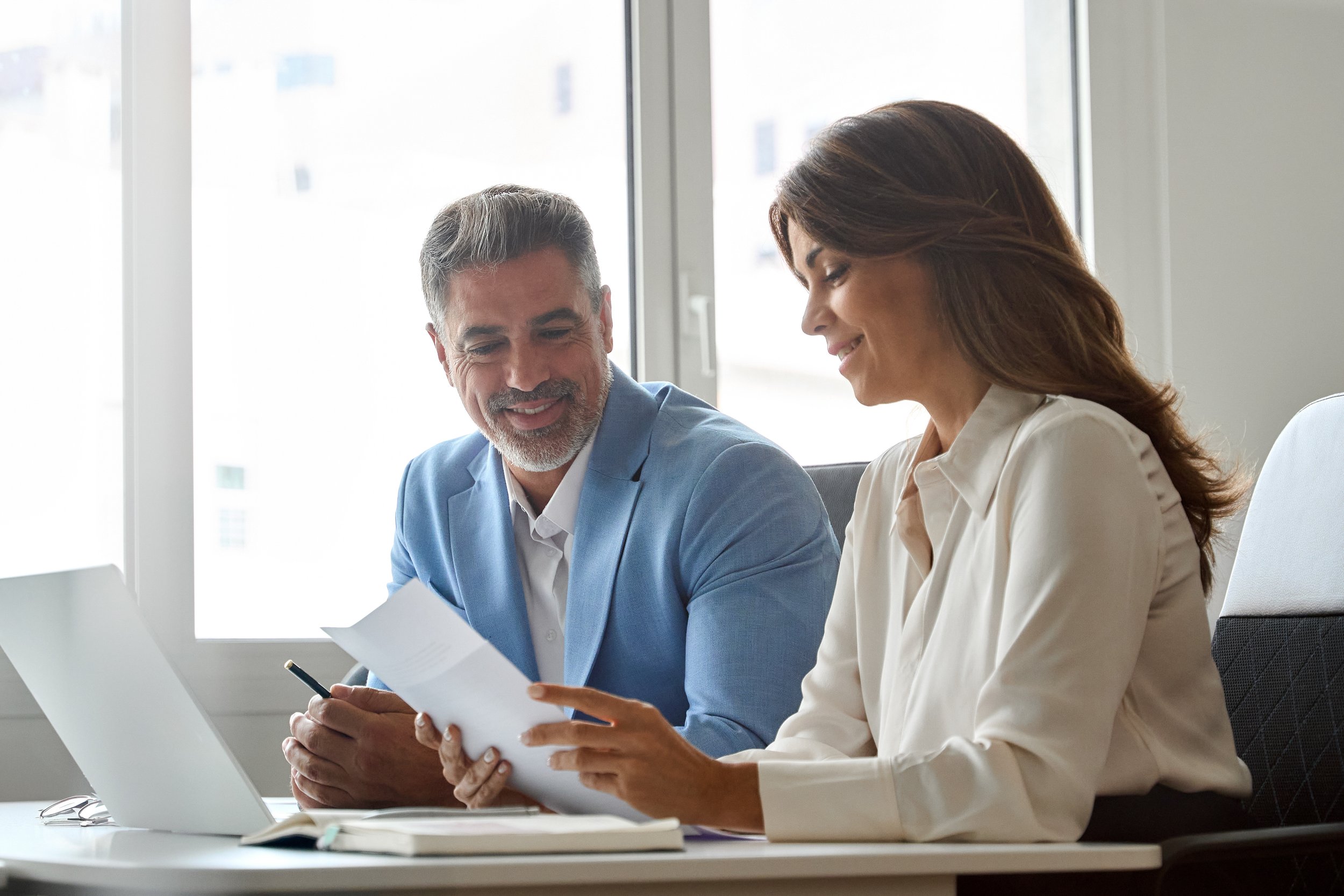 Man and woman sit at desk. Cisco employees: learn how the mega backdoor Roth lets you contribute up to $72,000 annually to your 401(k) and convert after-tax dollars to tax-free Roth savings.