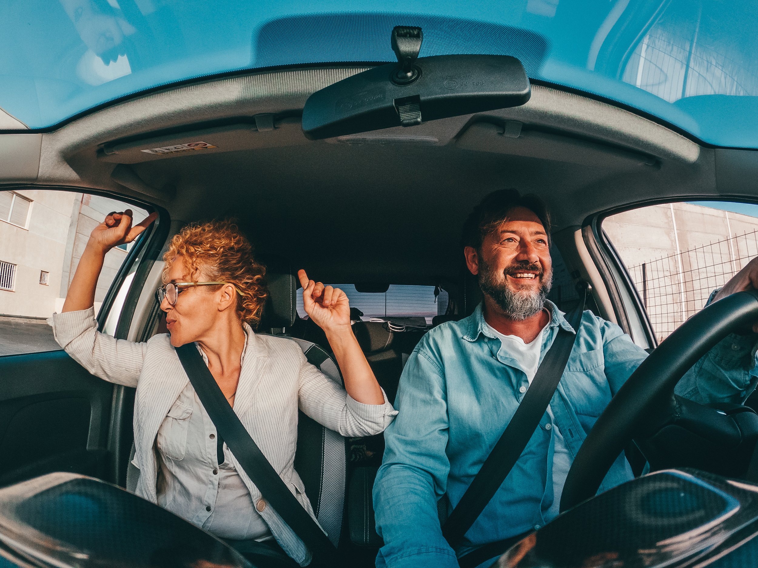 A middle-aged couple riding in the car together.  Thinking about early retirement from Cisco? Explore the key pros and cons — from RSU vesting and the Medicare gap to healthcare costs and tax strategies — so you can make the right call.