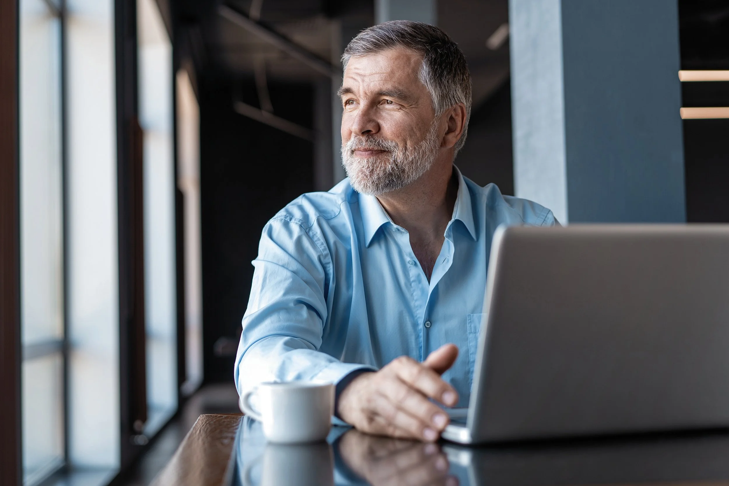 A senior business professional gazes out the window while working on his laptop. For high-earners at Microsoft, tax optimization is more than just a good idea - it's a financial necessity. With the right strategies, you can grow your wealth.