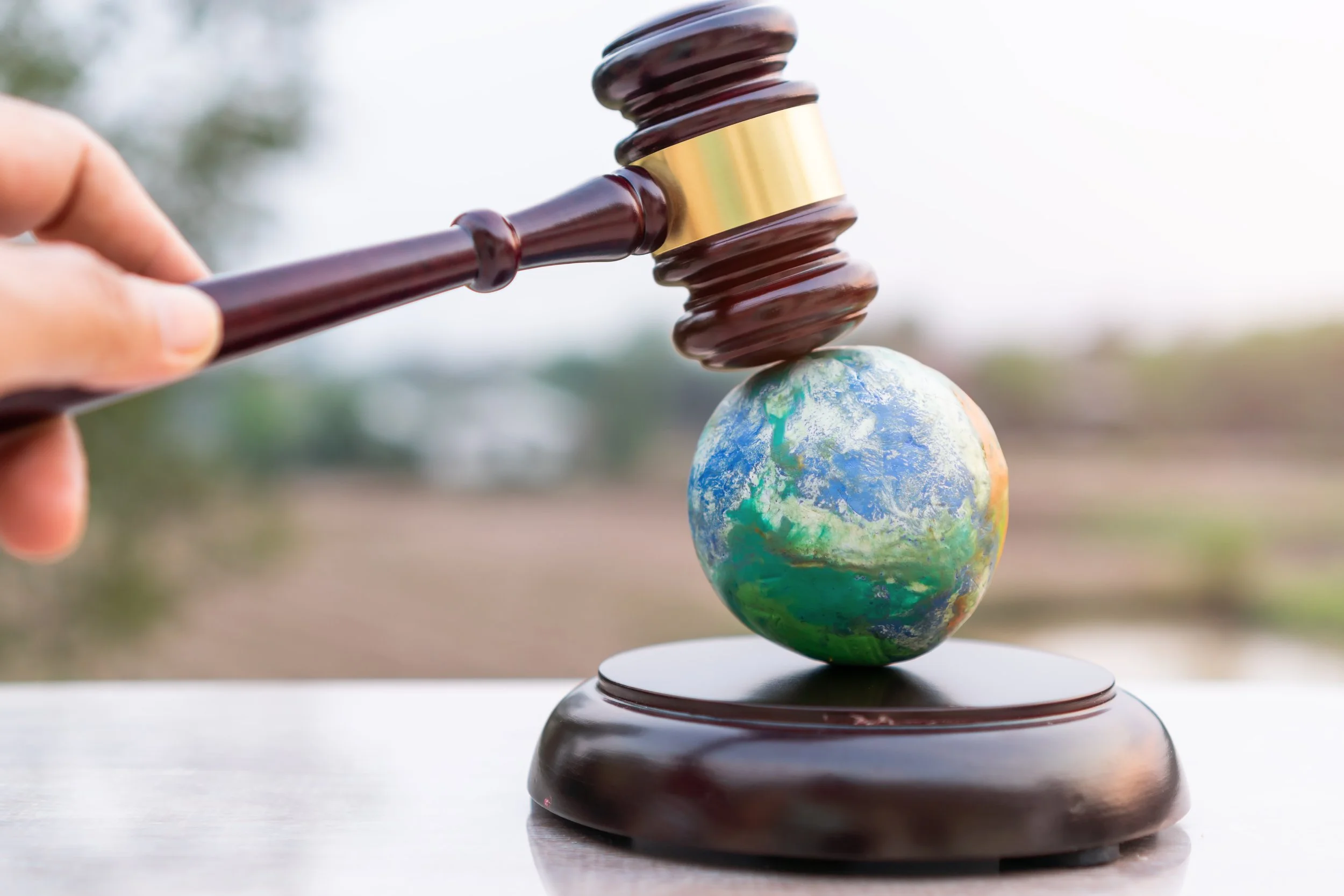 A gavel striking a globe with land and water features, symbolizing law and the world.