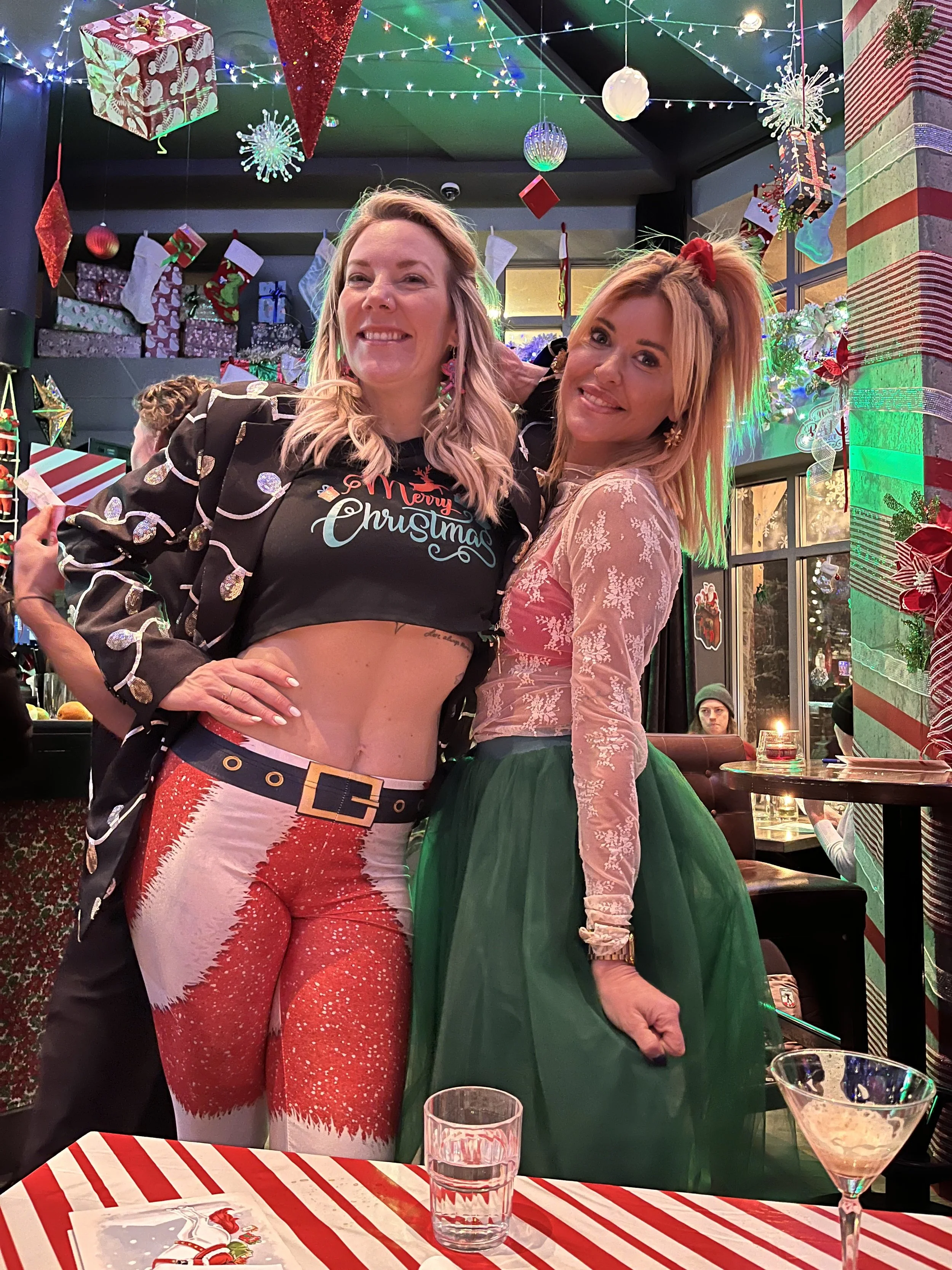 Brandi Woodnutt and friend at Miracle Pop Up Bar at The Raven Room in Whistler BC Canada are smiling and posing for a photo at a Christmas celebration.